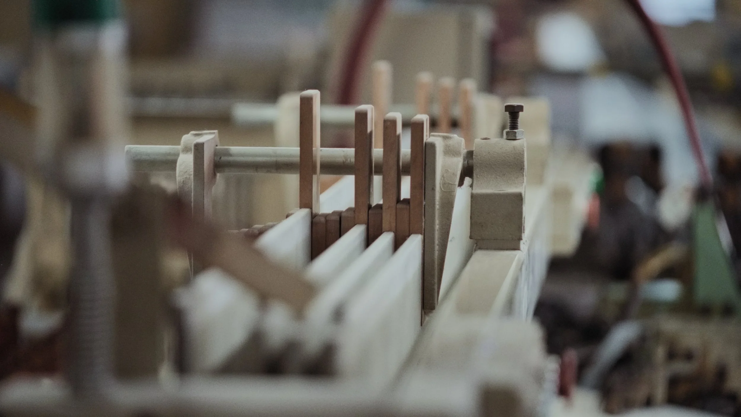 Close-up of a mechanical device with multiple vertical metal rods and threaded parts, with a blurred background.
