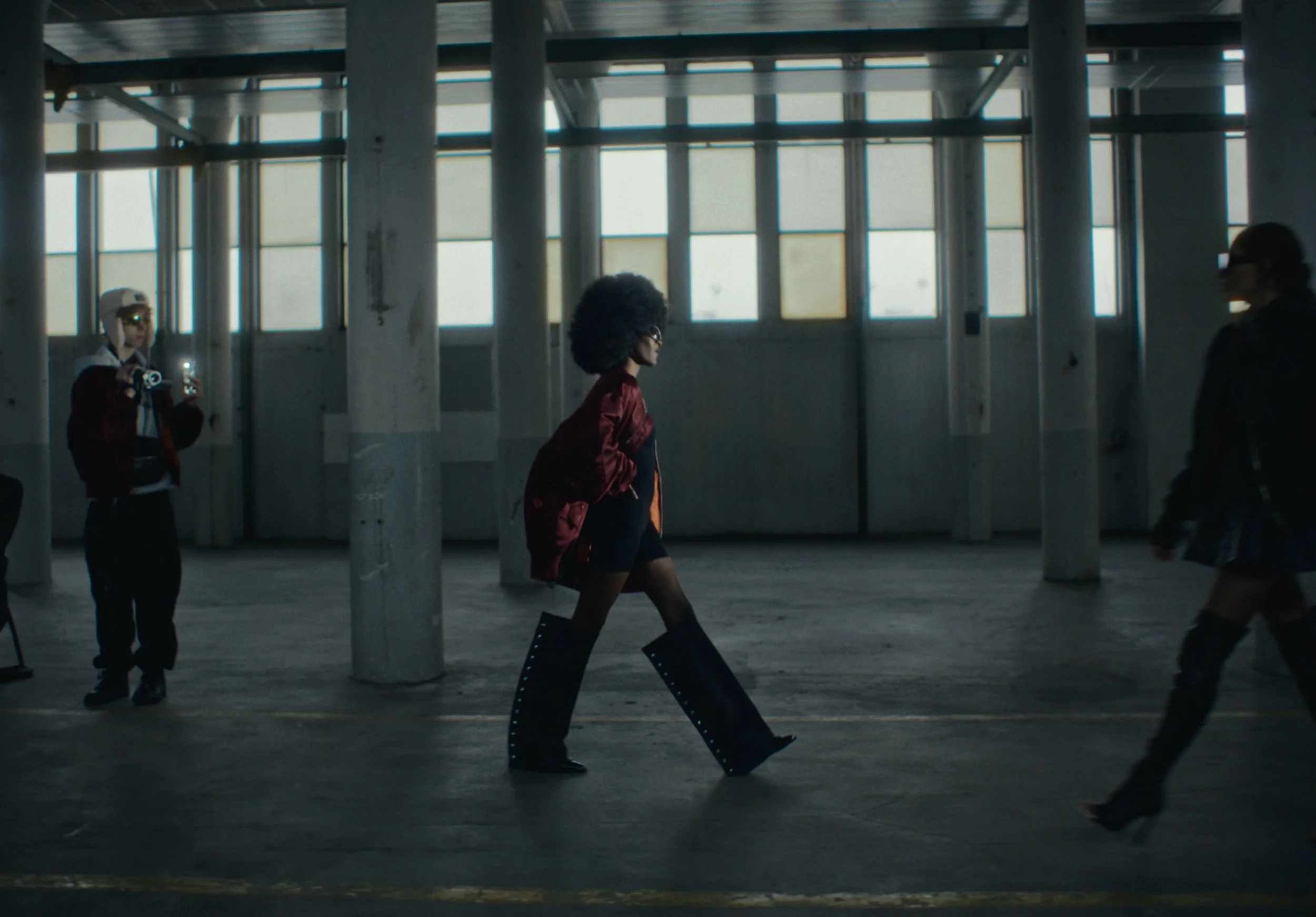 People walking in an industrial-style building with large windows and concrete pillars.