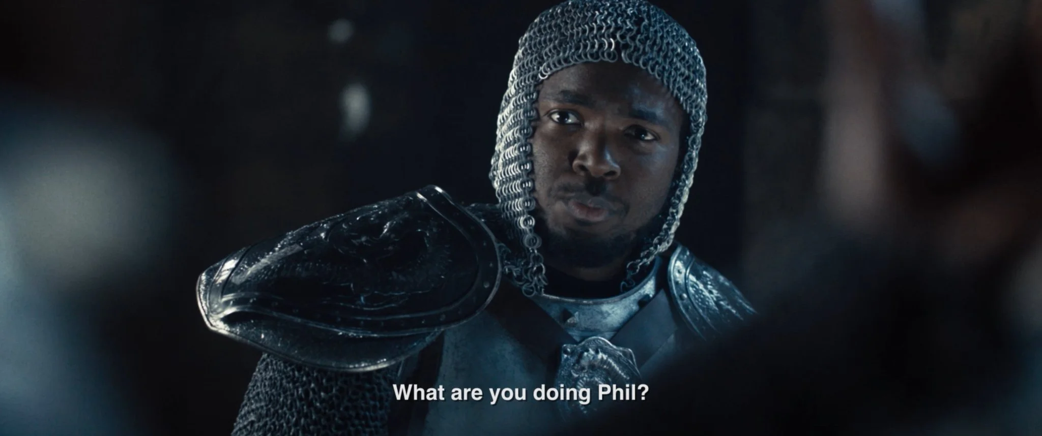 A man dressed as a medieval knight with chainmail and armor, looking serious, with the subtitle 'What are you doing Phil?'