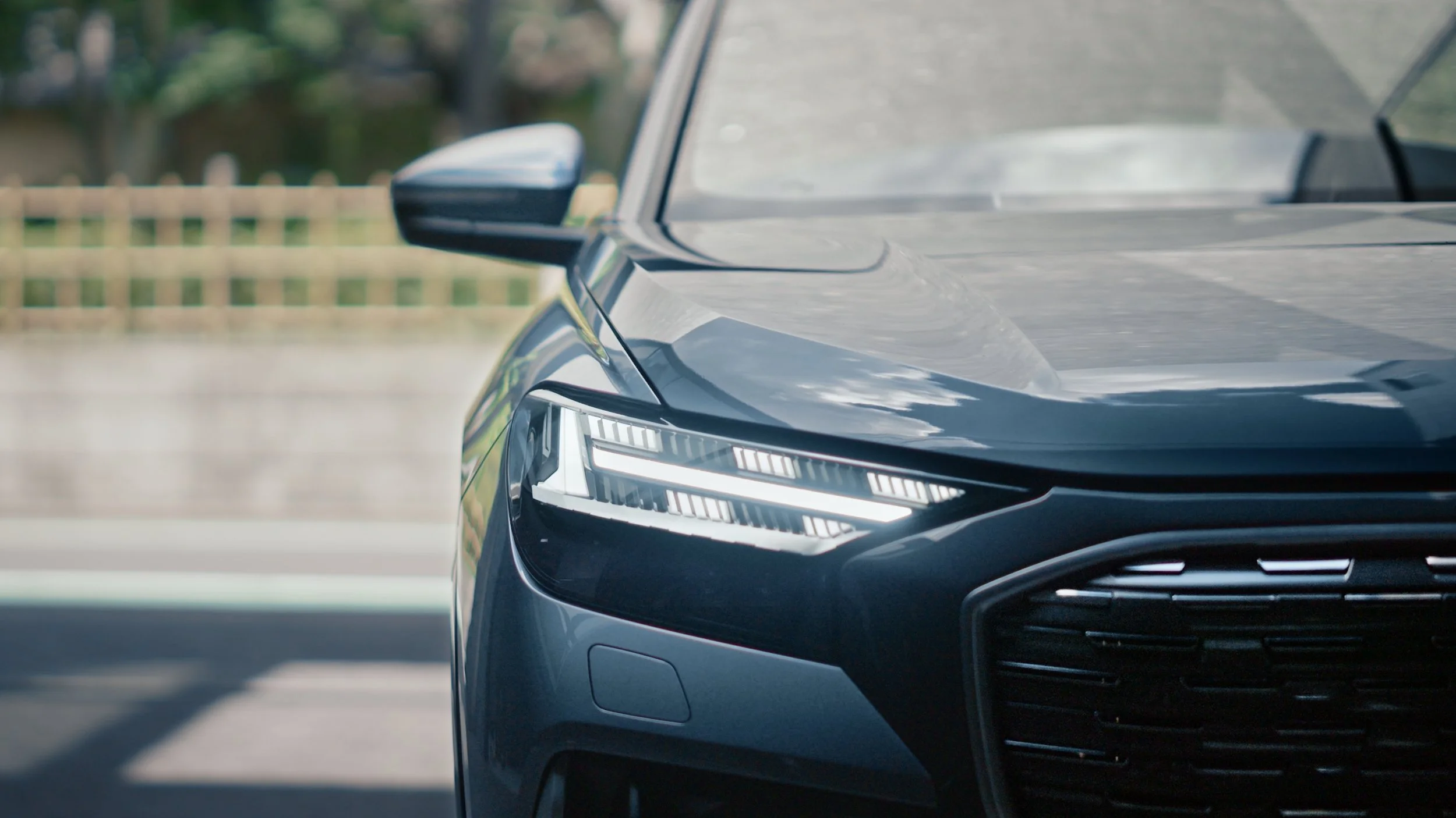 Close-up of the front right side of a black modern car, showing the headlight and side mirror.
