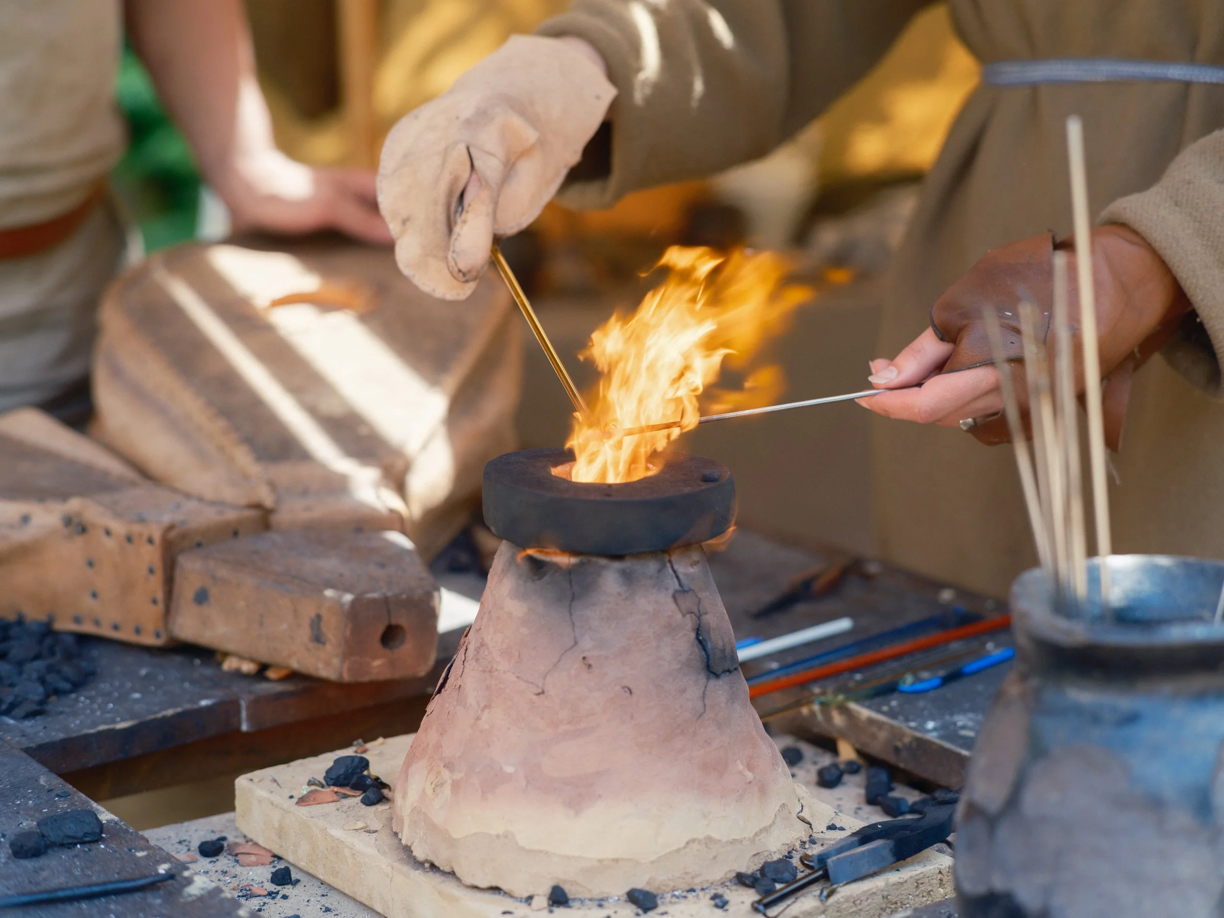 Person working with fire and clay in a pottery studio, shaping a clay piece on a clay pedestal.