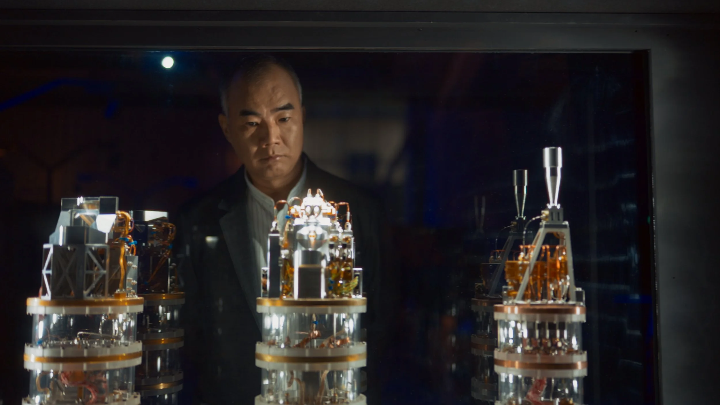 A man looks at a display case with intricate machinery or robotic models inside a glass enclosure.