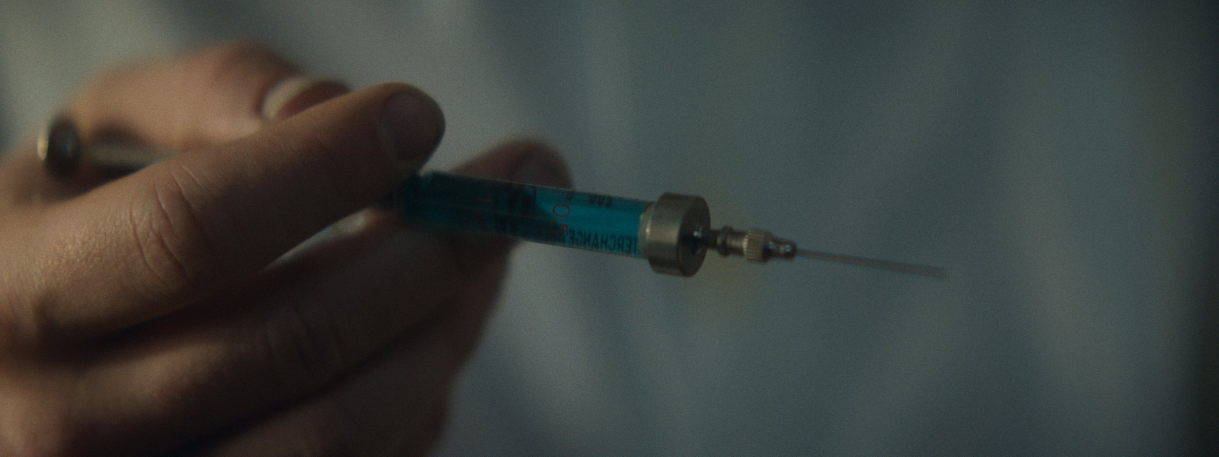 Close-up of a hand holding a syringe with a needle, ready for injection.
