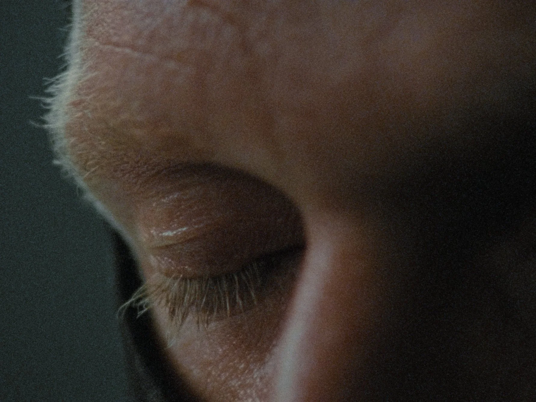 Close-up of a person's eye with closed eyelids and long eyelashes.
