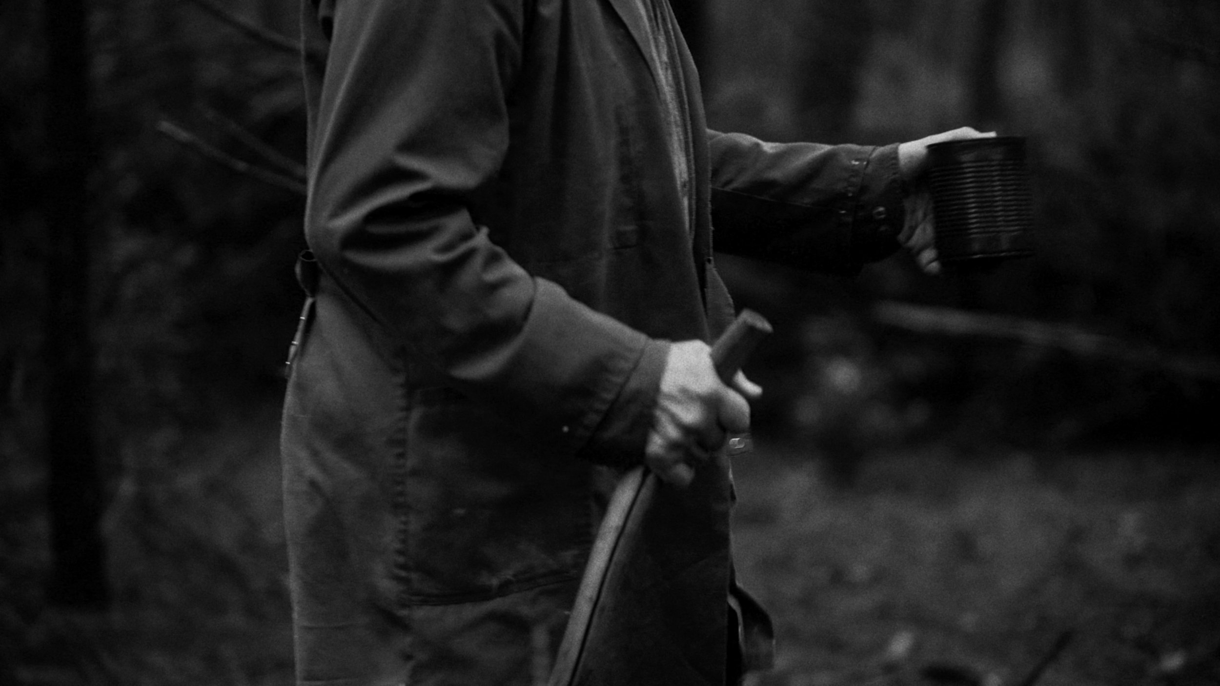 A person wearing a jacket and gloves holding a metal detector in an outdoor setting.