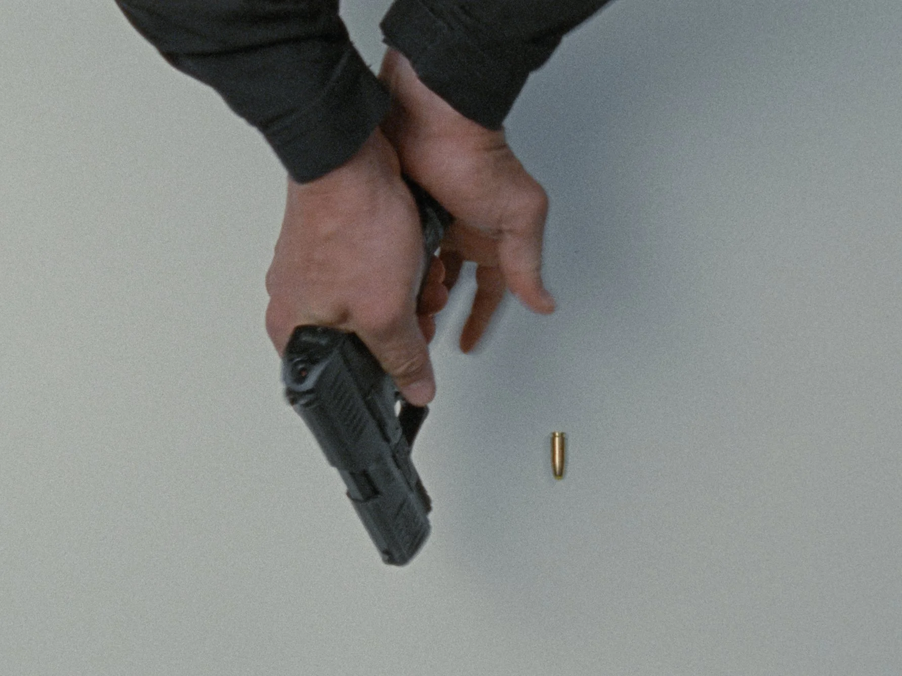 Person holding a handgun with a bullet casing on the surface.
