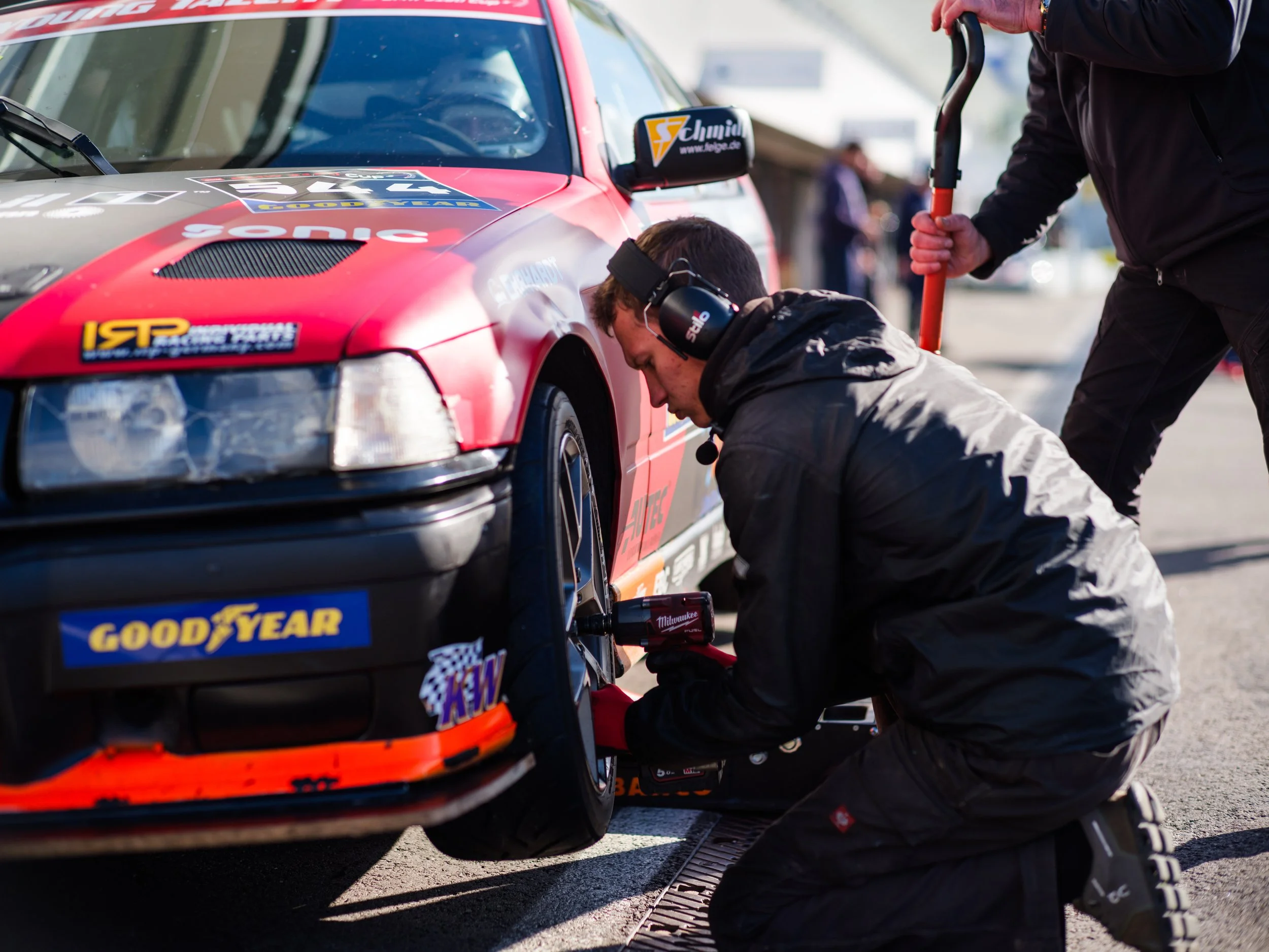Race car in the pit lane being worked on by mechanics during a motorsport event.