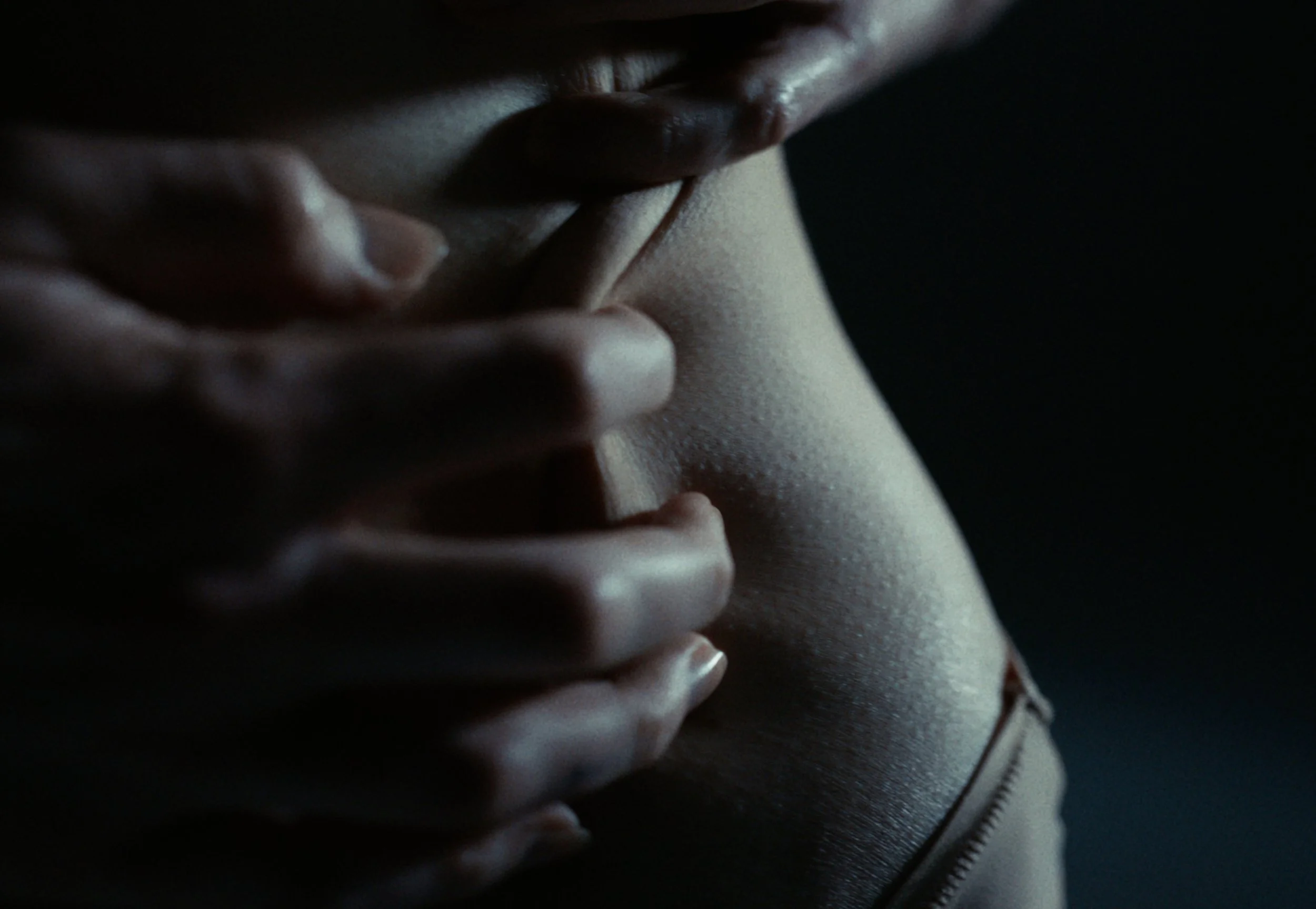 Close-up of a person's face, showing lips, nose, and part of a hand near the mouth, with a dark background.