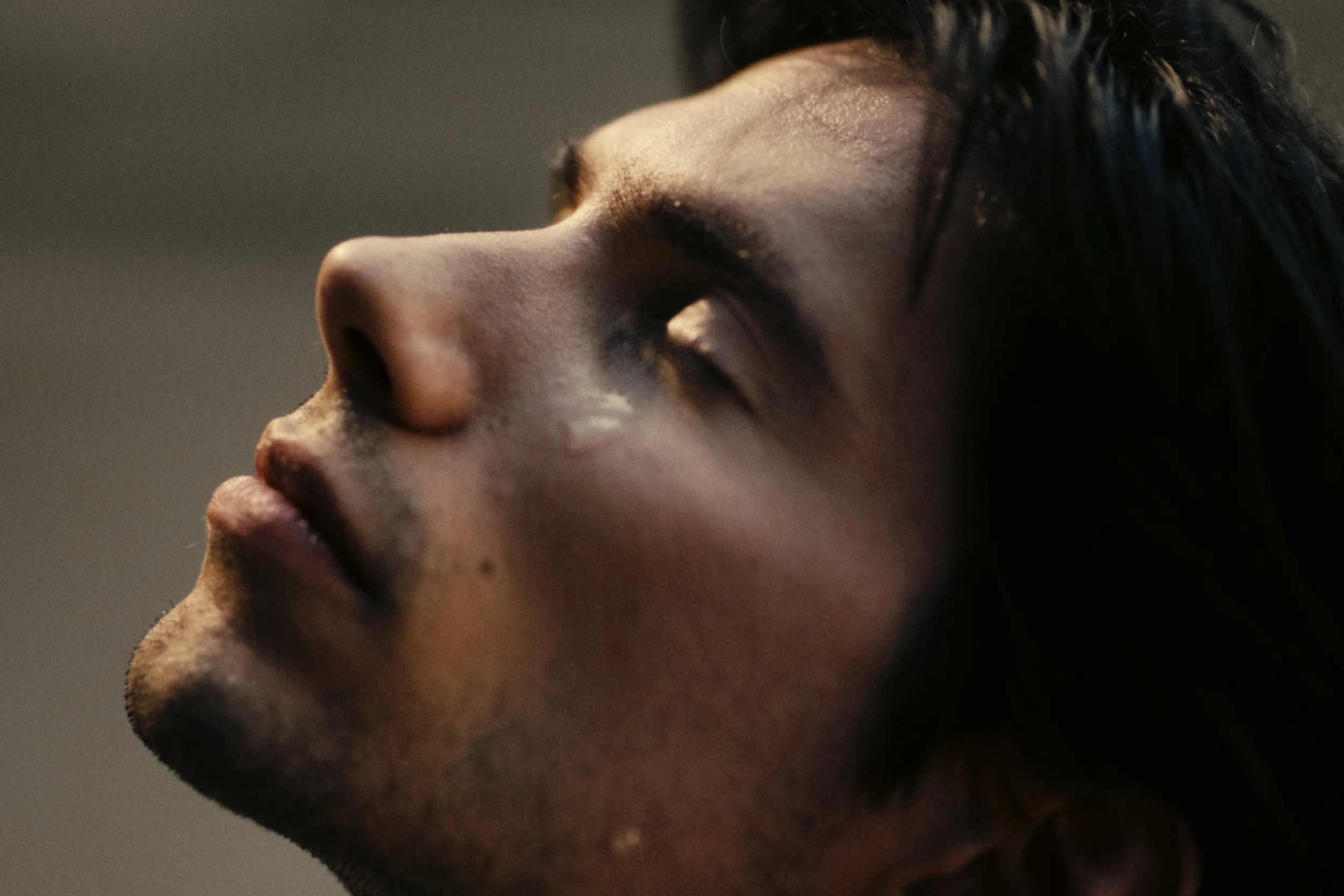 Close-up of a person's face in profile with closed eyes and dark hair, showing a serene expression.