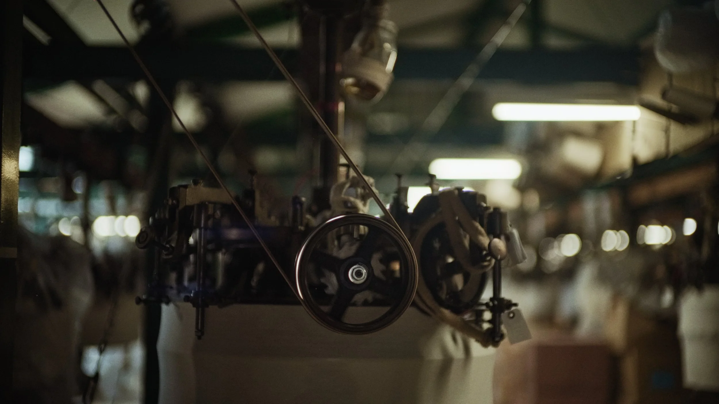 Close-up of machinery or mechanical equipment in a dimly lit setting, with gears, pulleys, and wires visible.