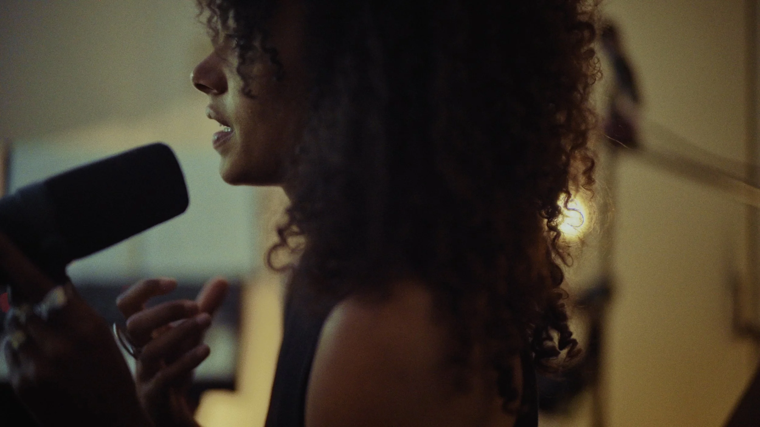 A woman with curly hair speaking into a microphone.