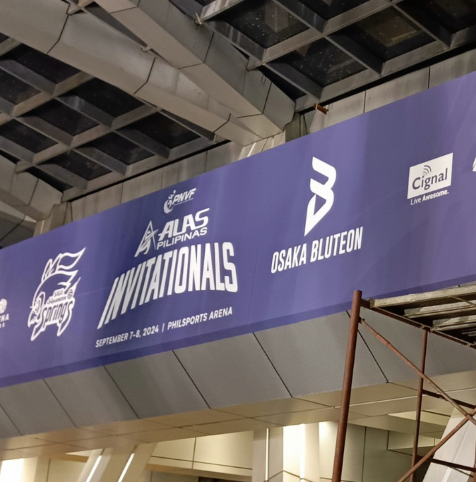 Blue banner hanging indoors promoting the ALAS Pilipinas Invitational sports event at PHILSORTS Arena on September 7-8, 2024. The banner features logos, text, and sponsor information.