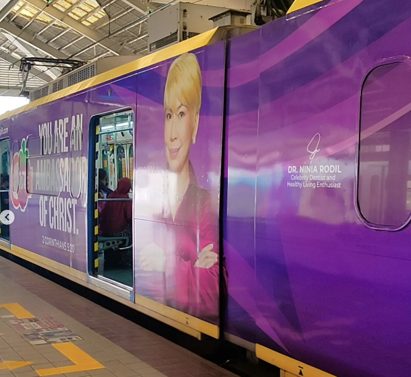 A purple train car with a large portrait of Dr. Nina Rodil, a celebrity dentist and healthy living enthusiast, inside a station, with text promoting good oral health.