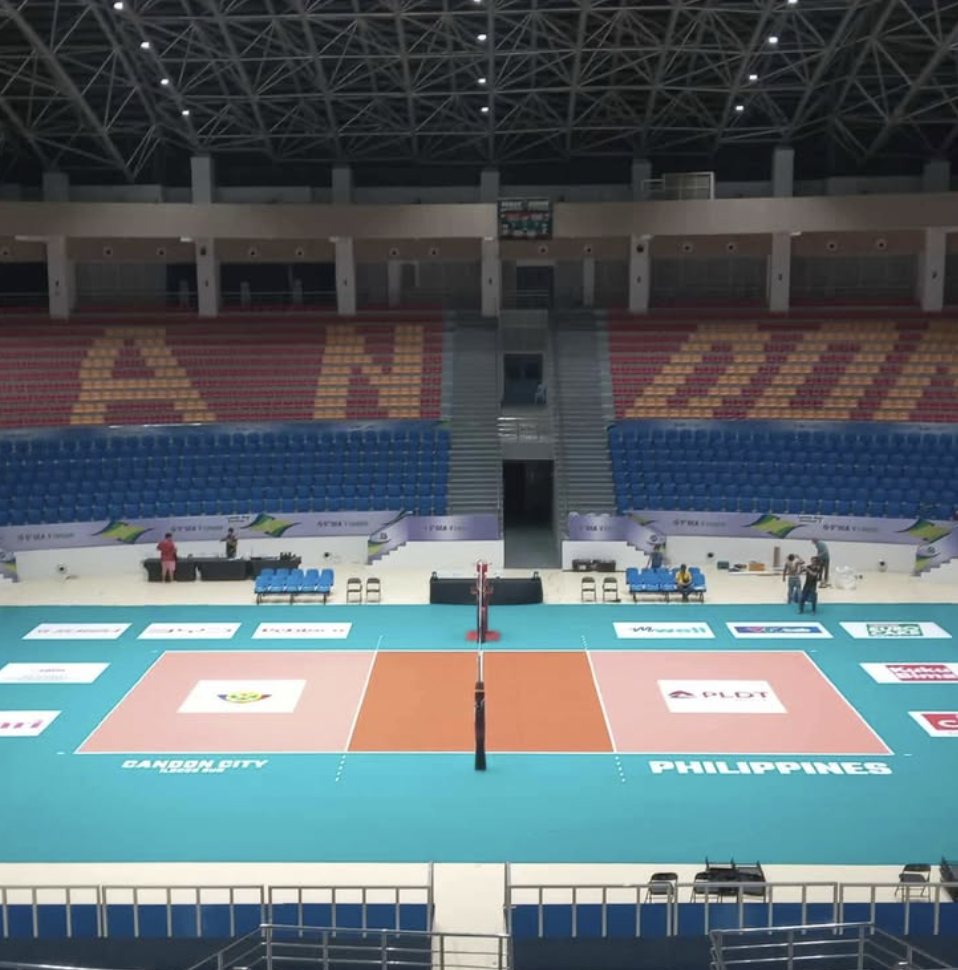 An indoor volleyball court set up in a stadium with seats and signs for the Philippines and Davao City.