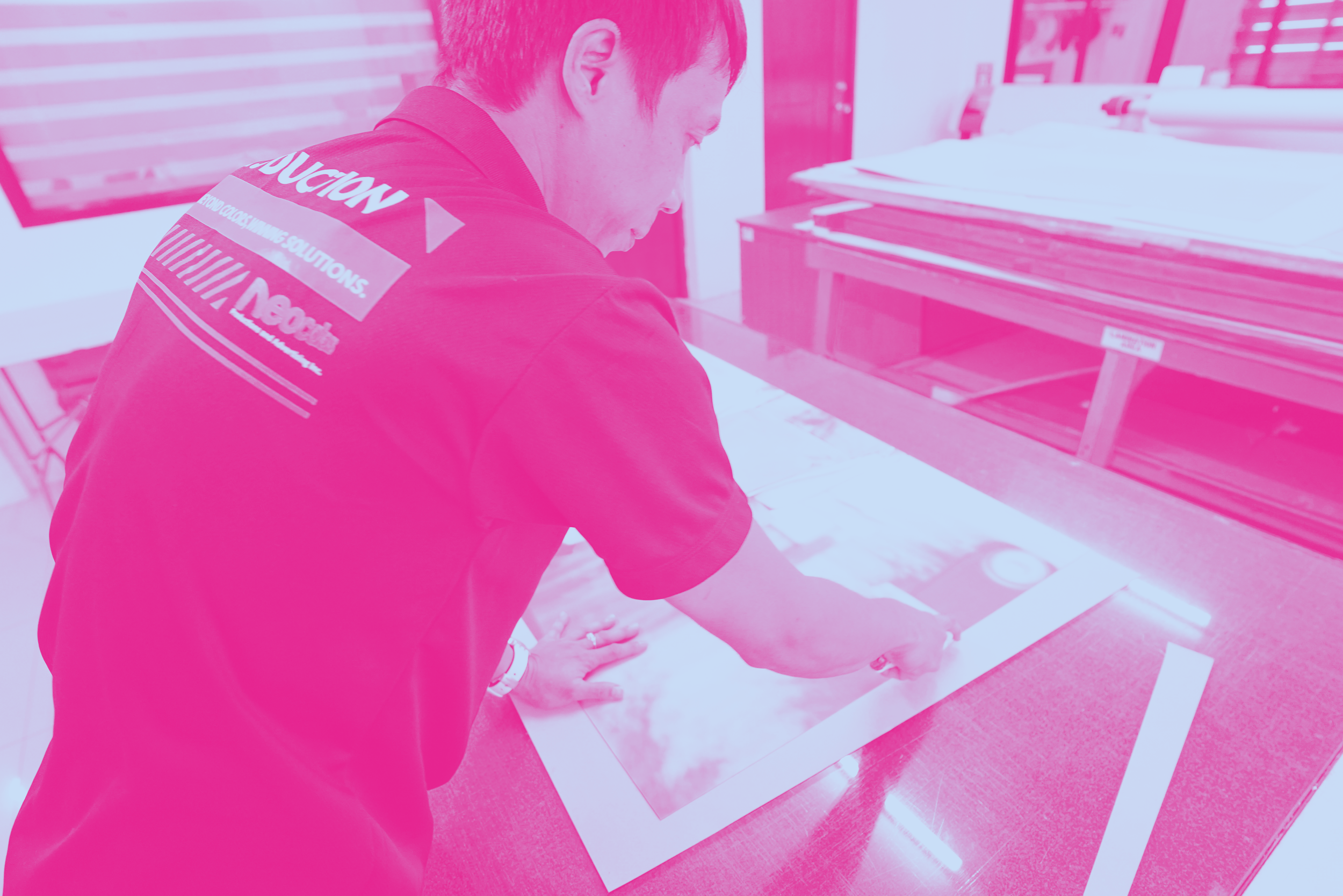 Person leaning over a display table examining photographs or prints in a workshop or studio setting.