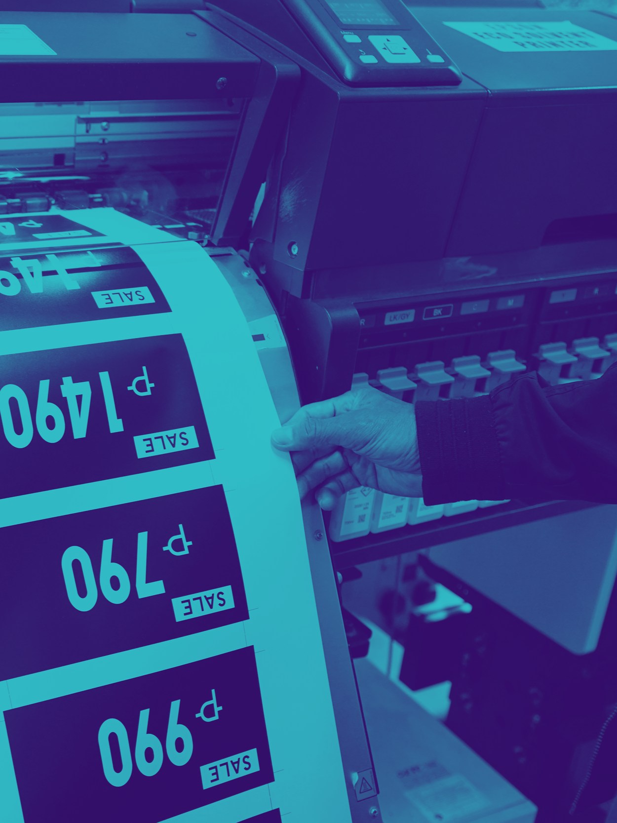 A person operating a large digital printer printing labels with prices