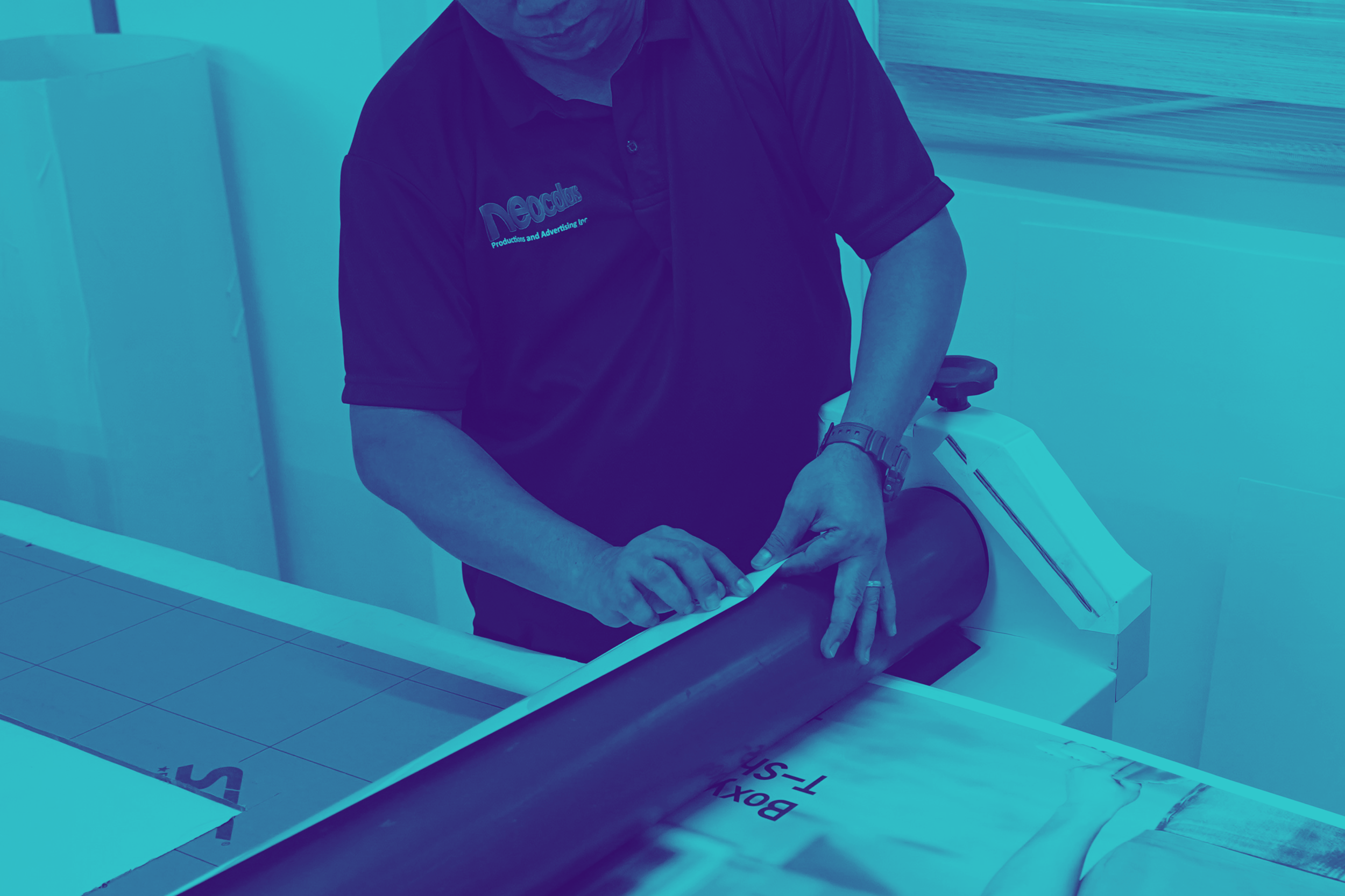A person wearing a black shirt with a logo that says "Neocolors Productions and Advertising Inc." is handling a white object