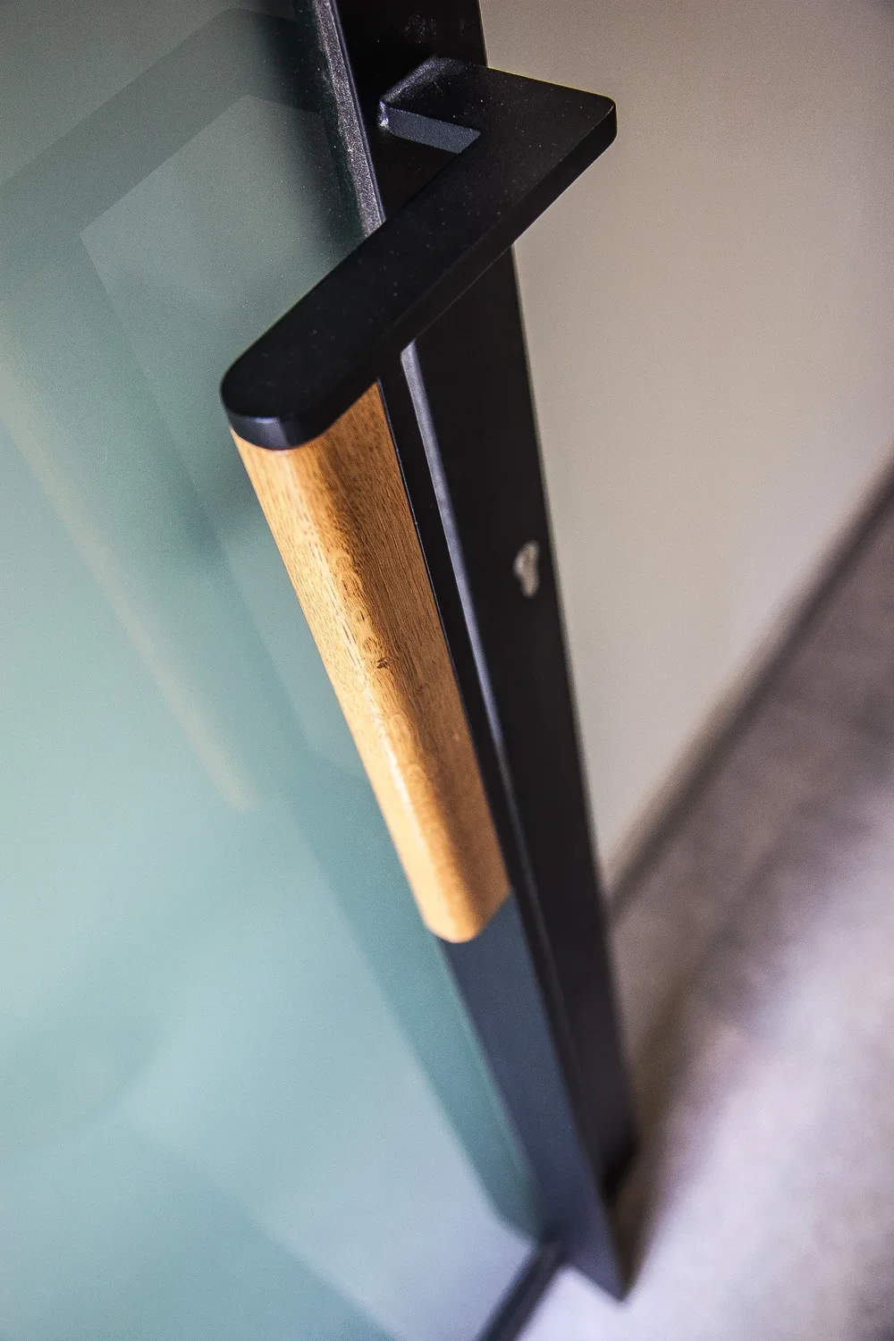 Close-up of a black door handle with a wooden accent on a modern door.