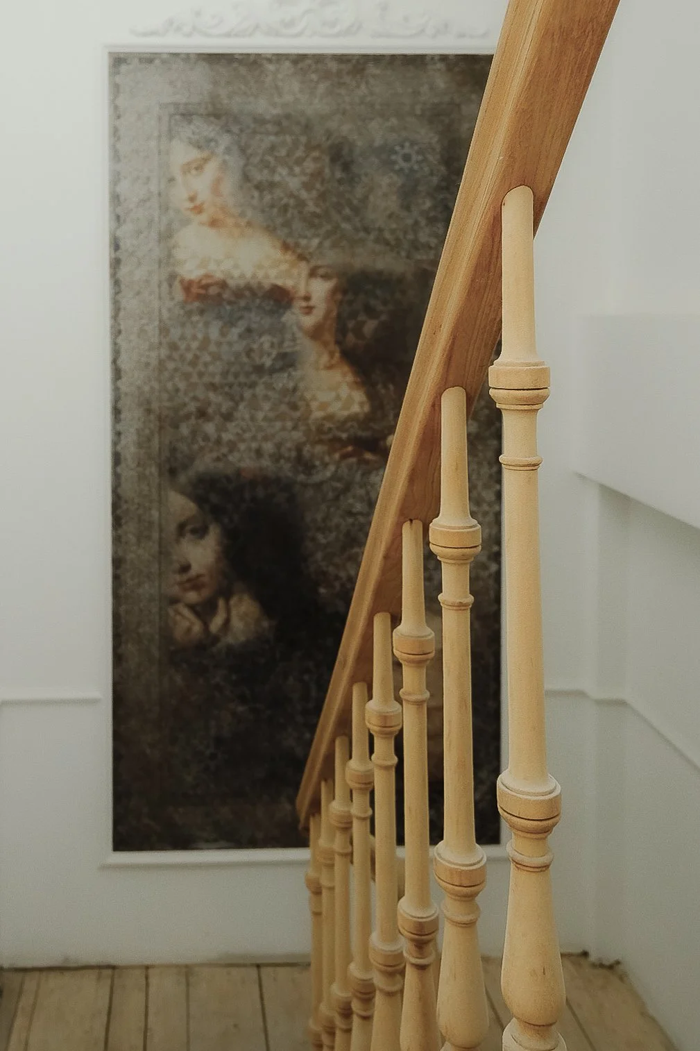 Bespoke interior integration of artwork near a classic wooden staircase railing, designed by Tom Naeyaert Architecture.