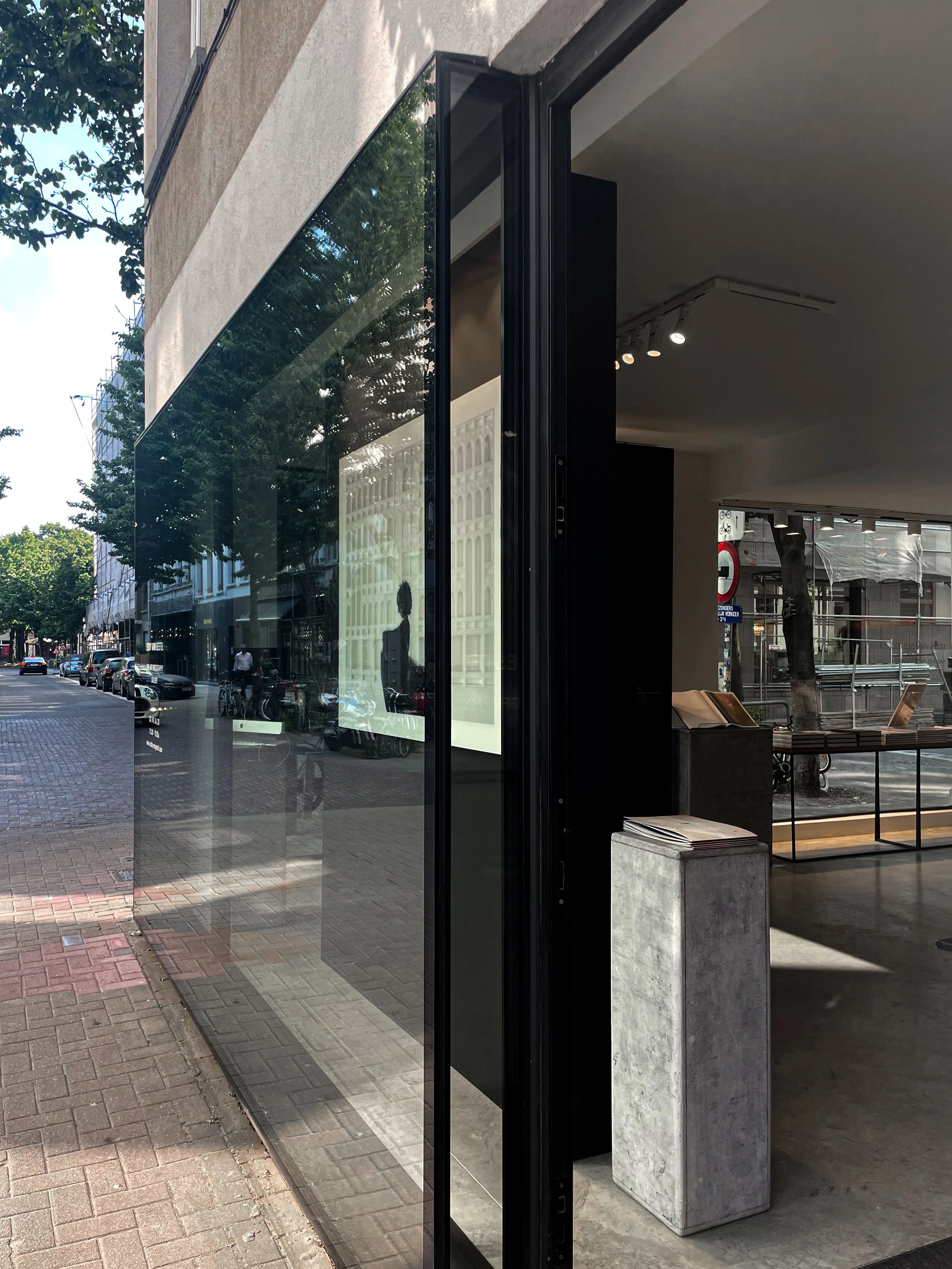Street view showing the reflective glass facade of a modern gallery project in Antwerp, designed by Tom Naeyaert Architecture.