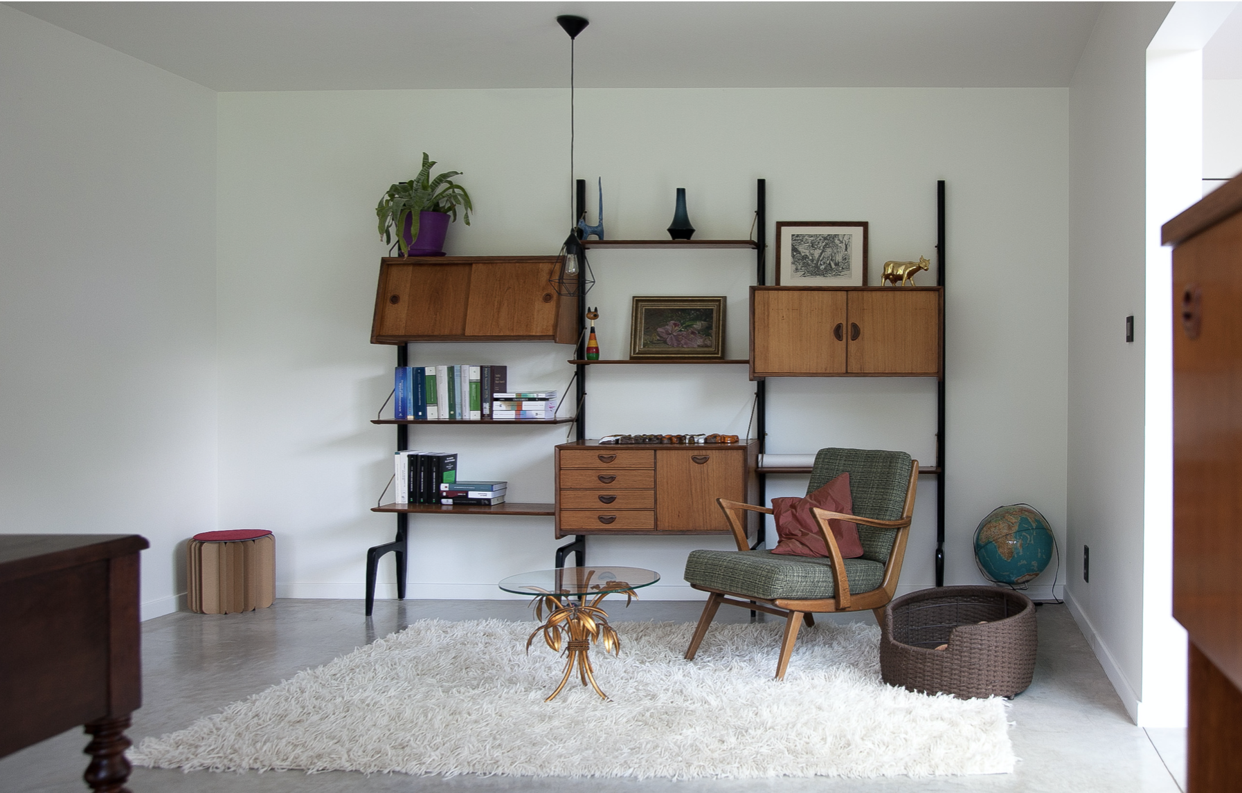 Mid-century modern residential living room design featuring a custom wall-mounted shelving unit, by Tom Naeyaert Architecture.