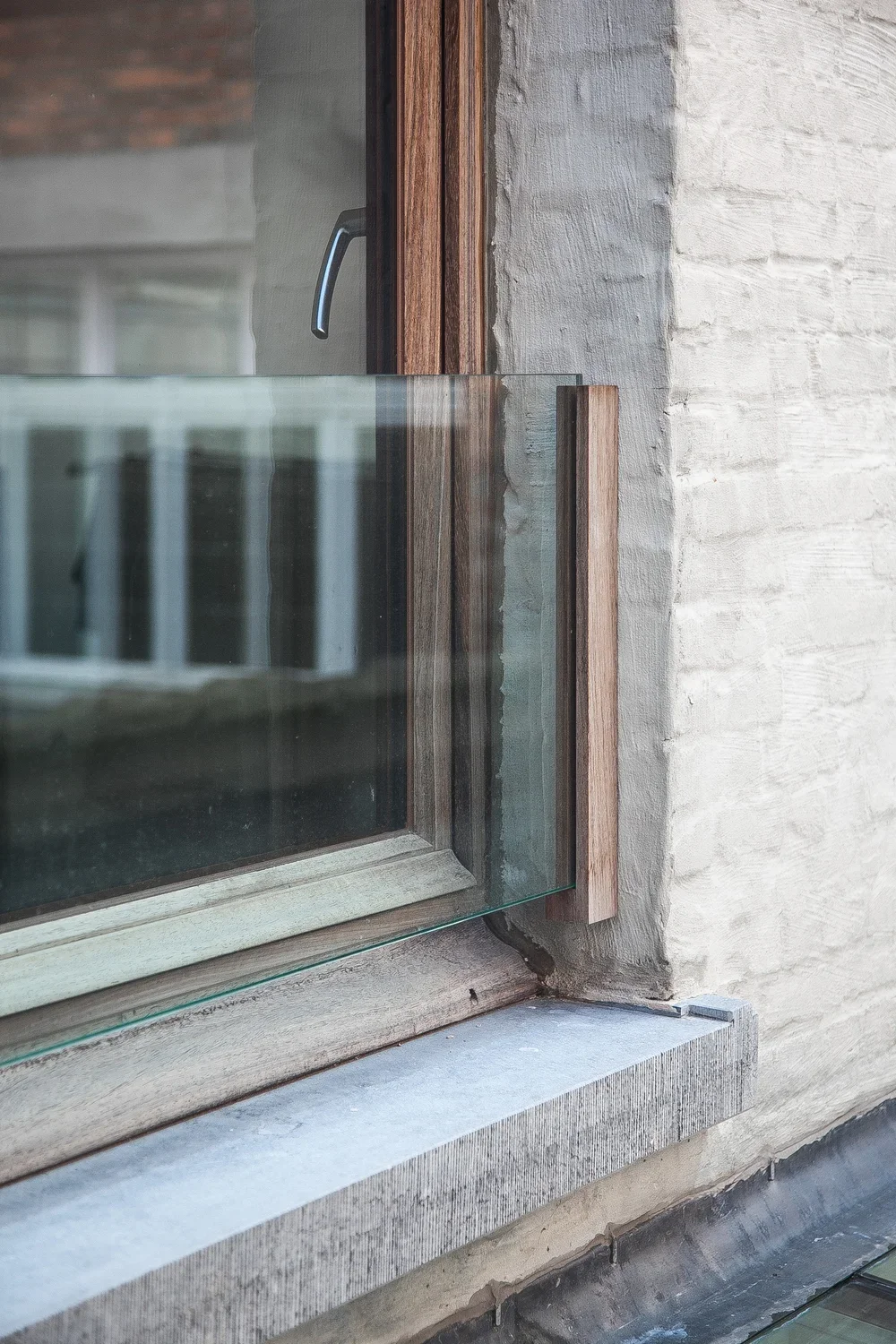 Close-up photo of a modern window with wooden trim, situated on a textured concrete wall.