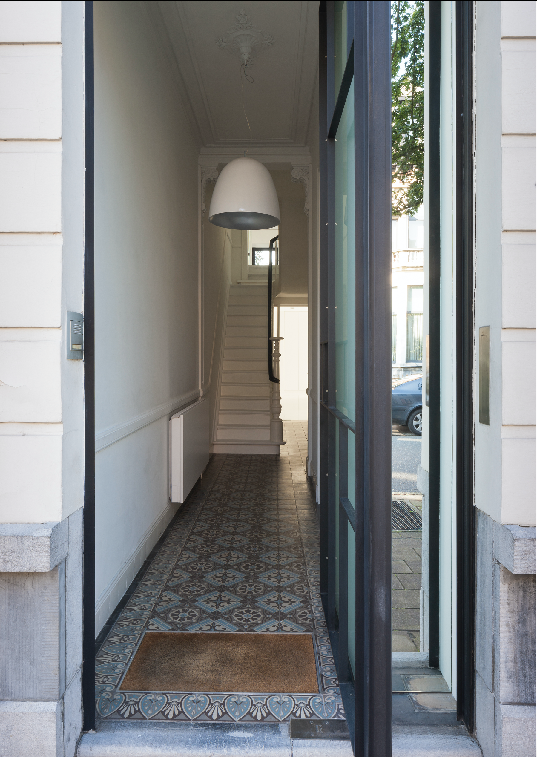 Bespoke hallway interior design featuring traditional patterned floor tiles and architectural lighting, crafted by Tom Naeyaert Architecture.