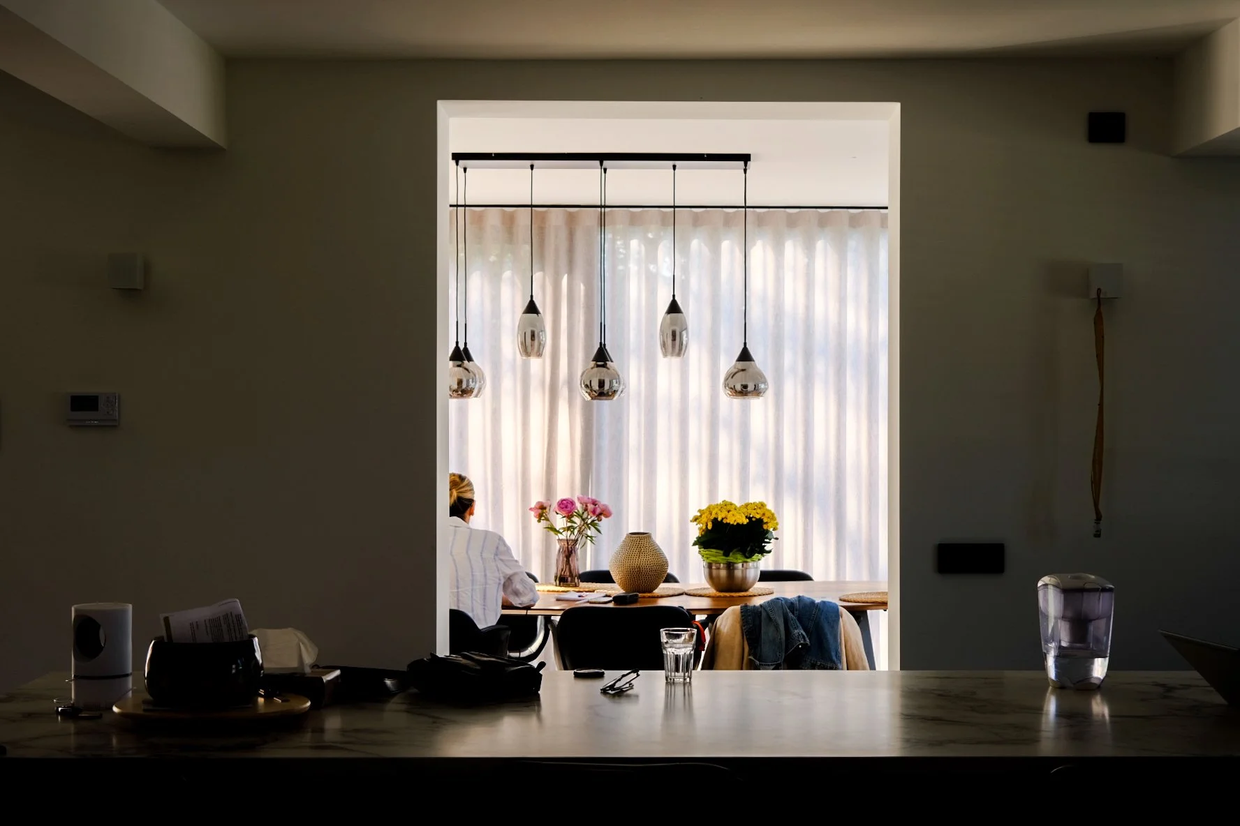 Bright and contemporary residential dining room interior featuring bespoke lighting fixtures, designed by Tom Naeyaert Architecture.
