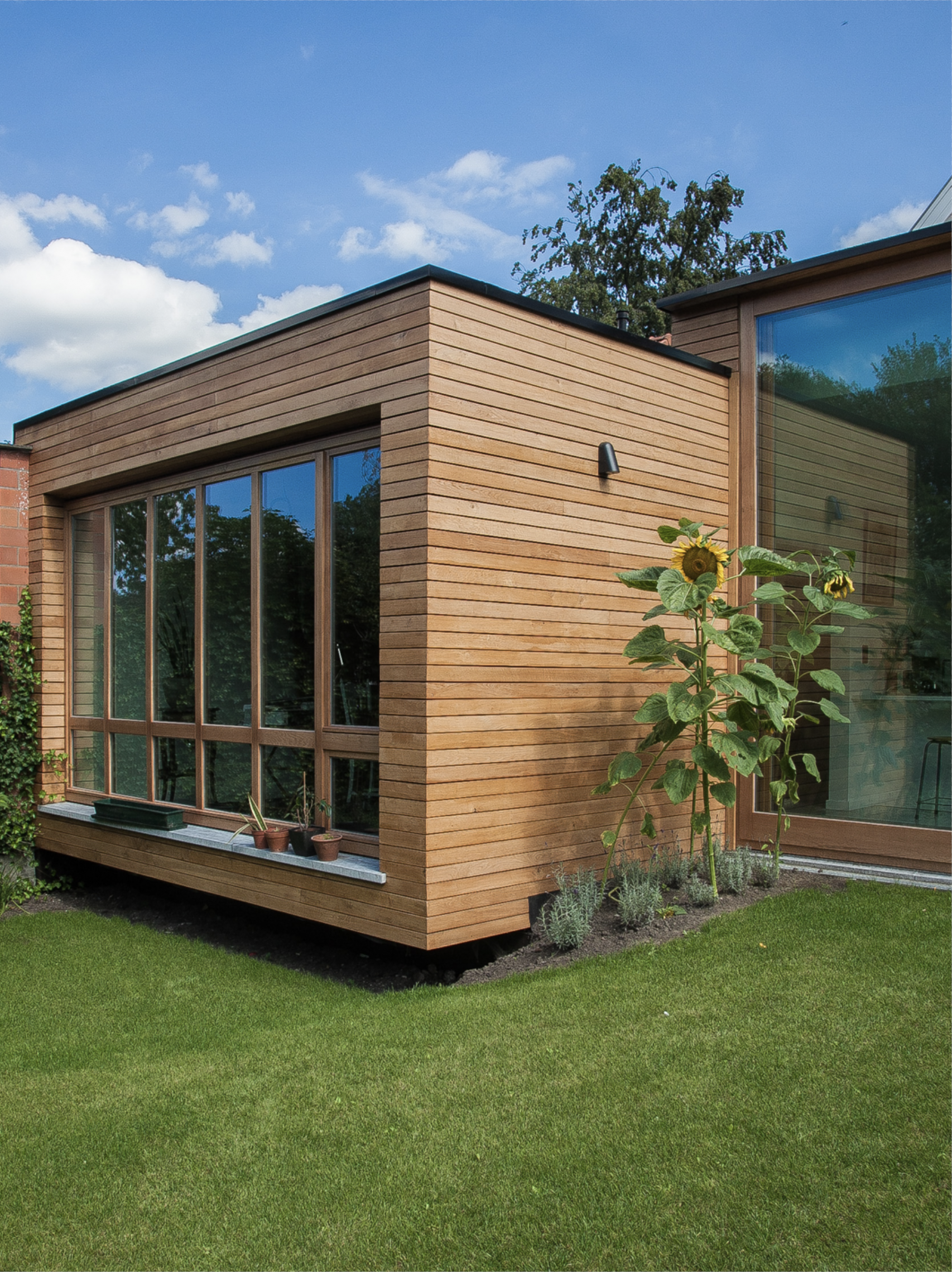 Modern residential house with a contemporary wooden exterior cladding and large windows, designed by Tom Naeyaert Architecture.