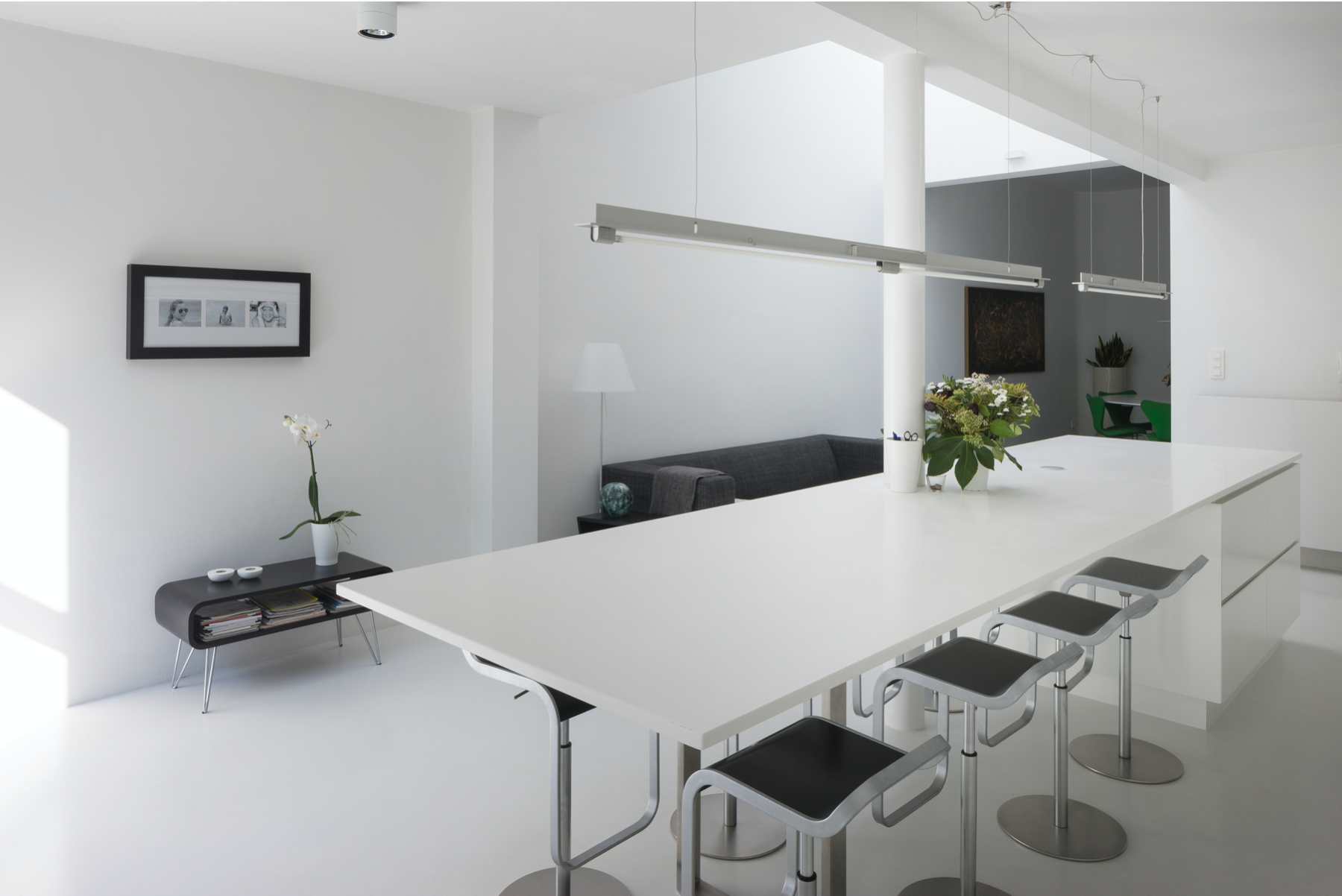 Minimalist residential kitchen design featuring a large bespoke white island and clean lines, crafted by Tom Naeyaert Architecture.