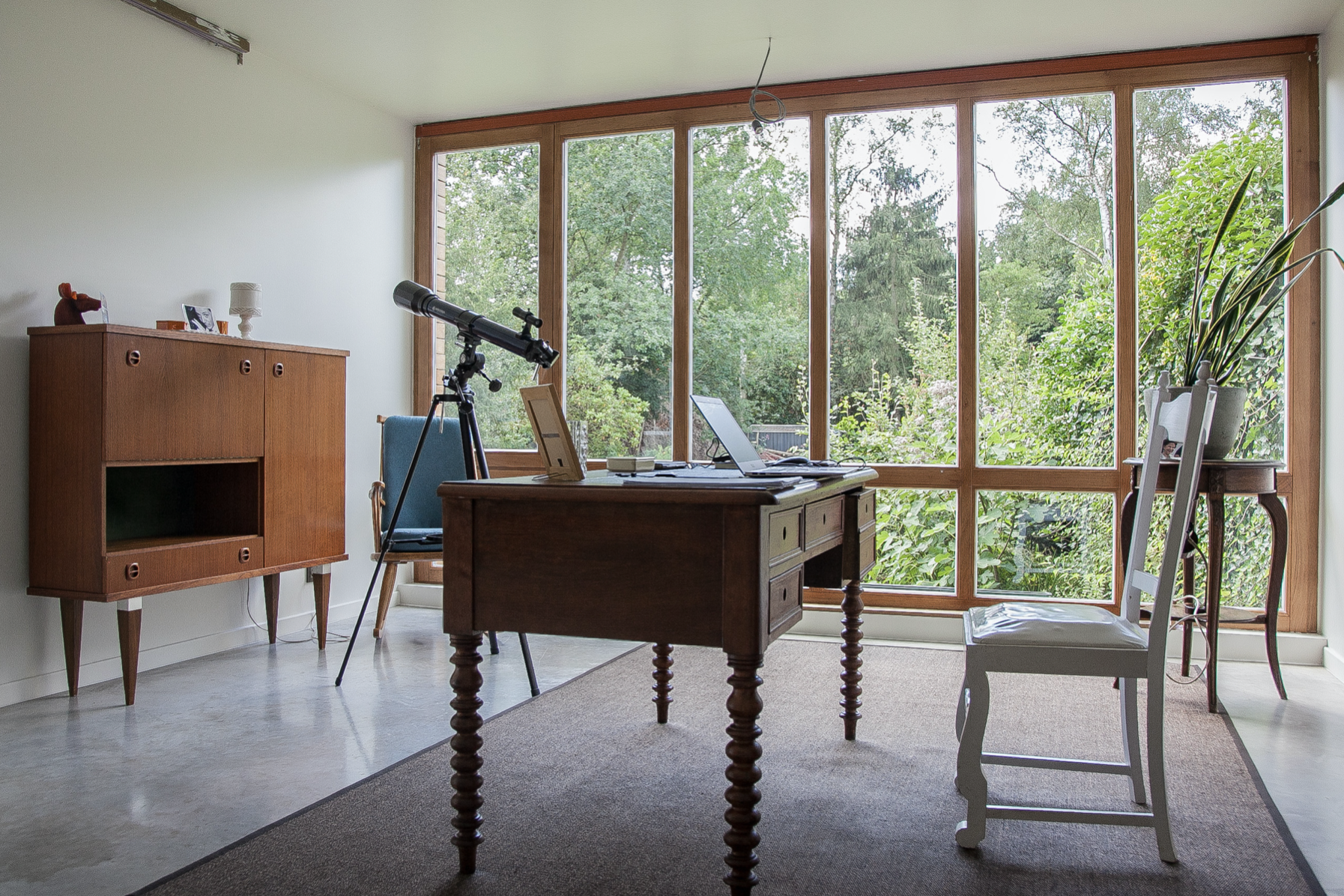 Bespoke home office interior design featuring mid-century modern furniture and a large window, designed by Tom Naeyaert Architecture.