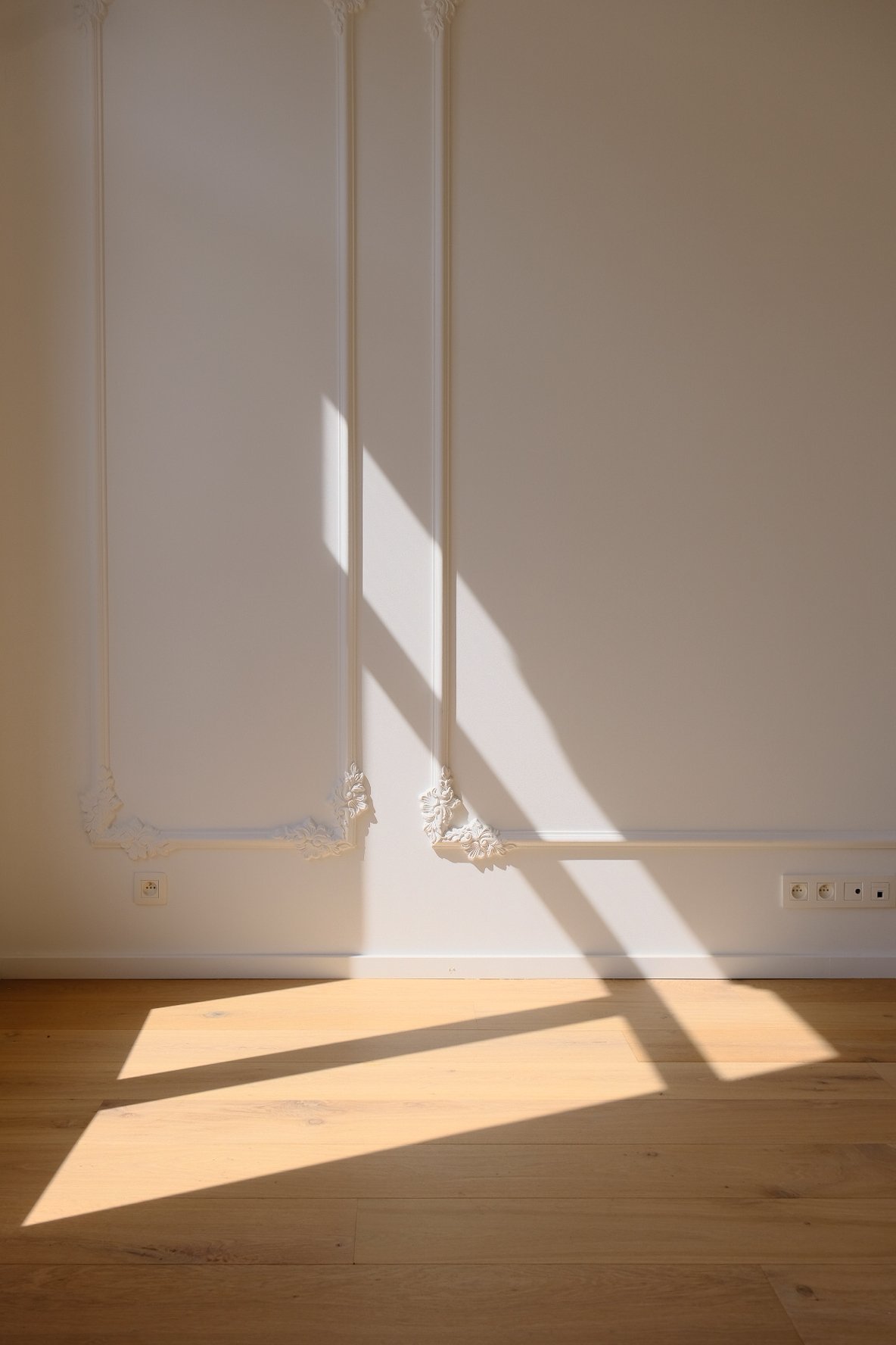 Historic townhouse renovation featuring white walls with ornate molding and a wooden floor, by Tom Naeyaert Architecture in Antwerp.