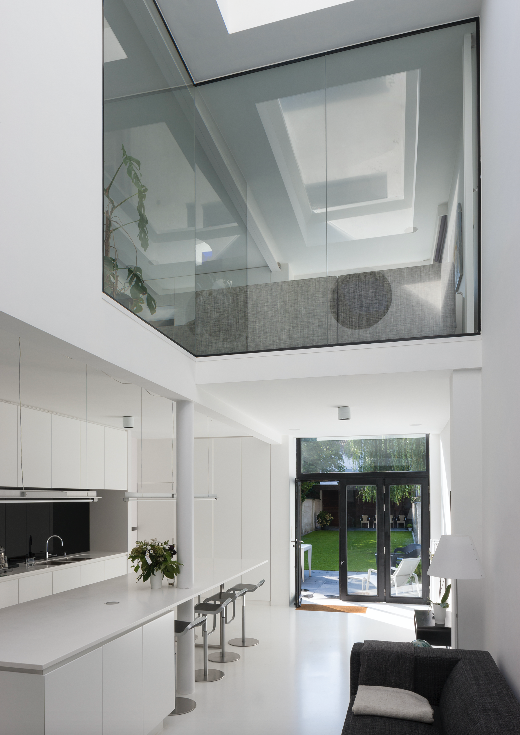 Modern open-plan kitchen and living area featuring a custom island and large glass doors to the backyard, designed by Tom Naeyaert Architecture.