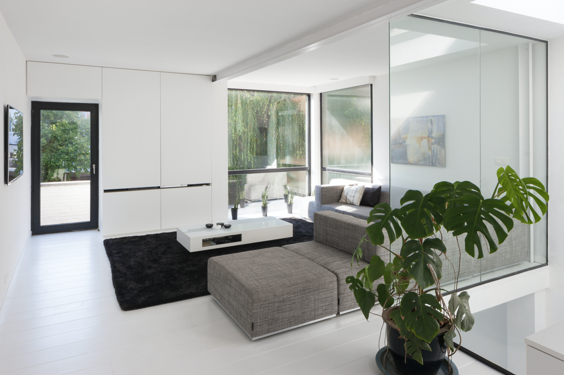 Minimalist residential interior design with white walls, large sliding glass doors, and bespoke layouts, crafted by Tom Naeyaert Architecture.