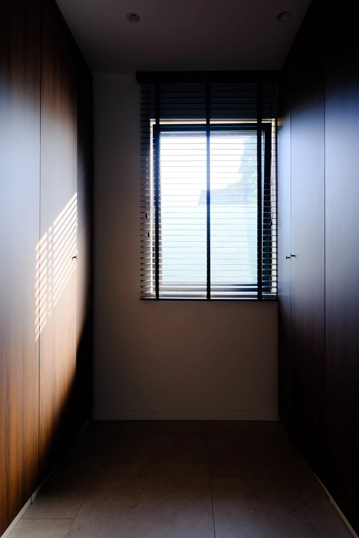 High-end custom dark wooden cabinetry in a narrow corridor, residential interior design by Tom Naeyaert Architecture.
