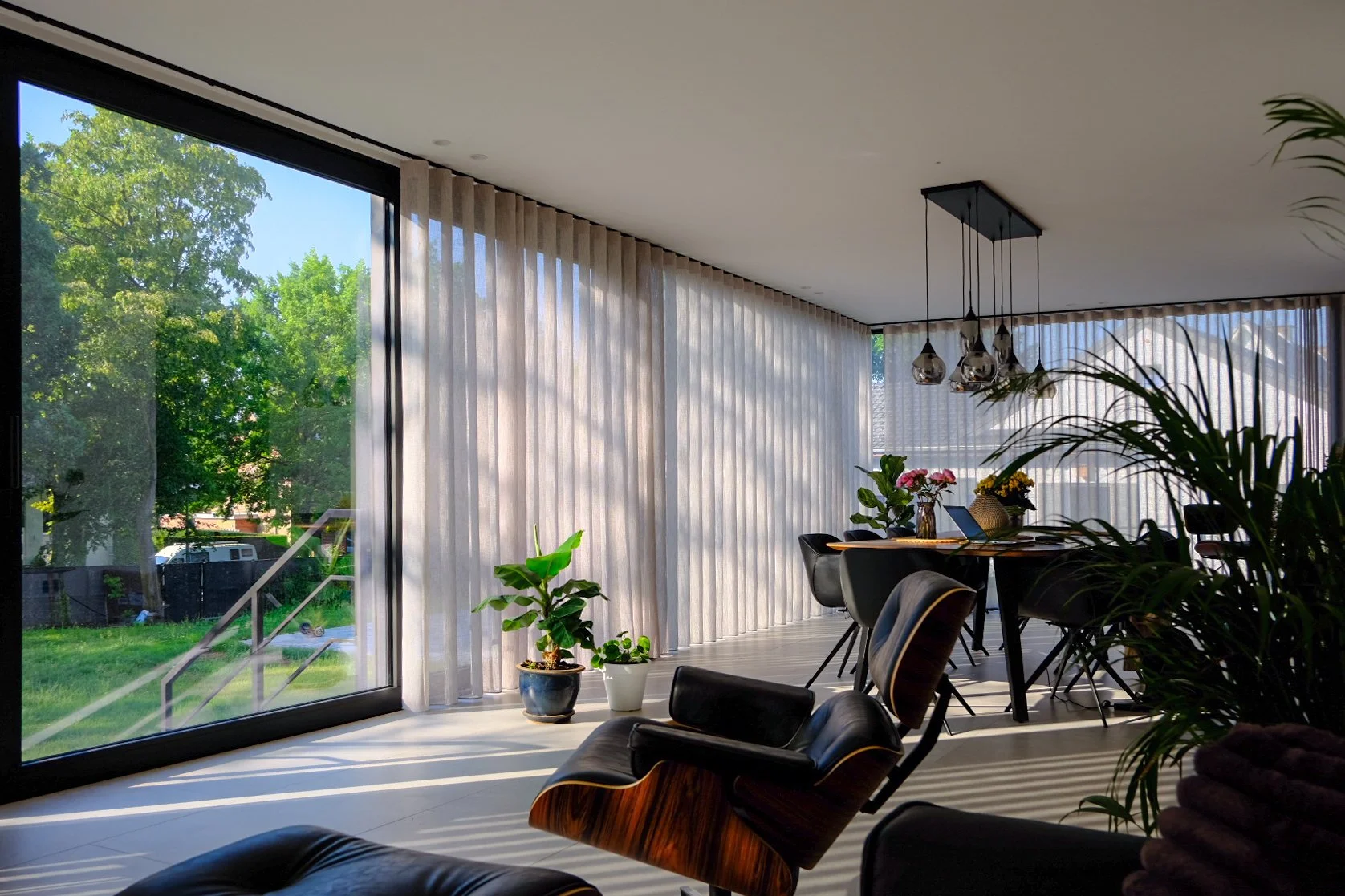 Modern residential living room design featuring large glass sliding doors and elegant pendant lights, by Tom Naeyaert Architecture.