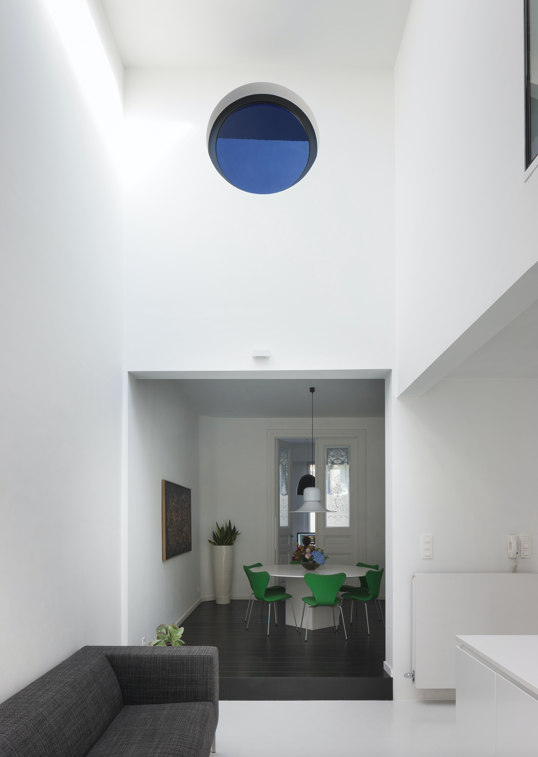 Contemporary interior architecture for a dining area with high ceilings and a minimalist design, by Tom Naeyaert Architecture in Antwerp.