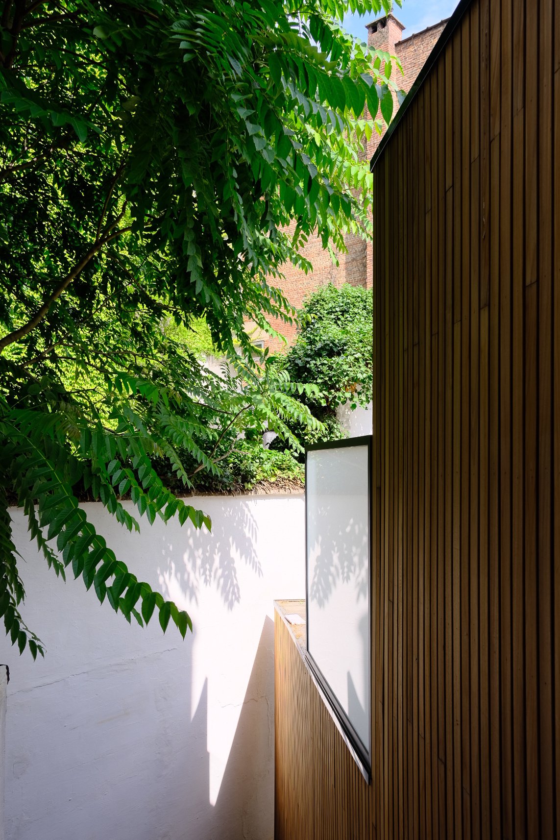 Contemporary residential architecture featuring a private balcony with wooden wall paneling, by Tom Naeyaert Architecture.