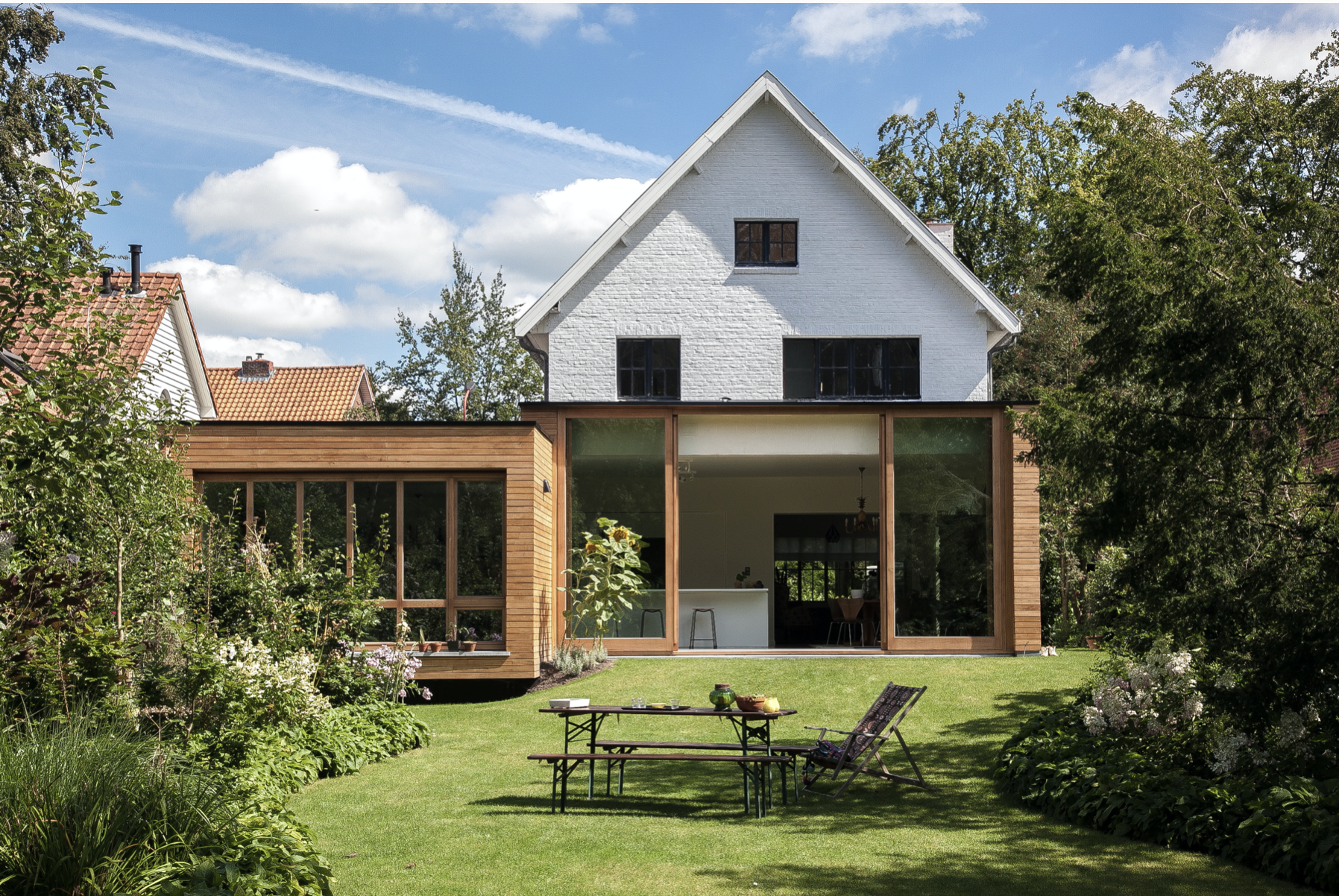 Contemporary residential architecture featuring a unique wooden house extension with large glass windows, by Tom Naeyaert Architecture in Antwerp.