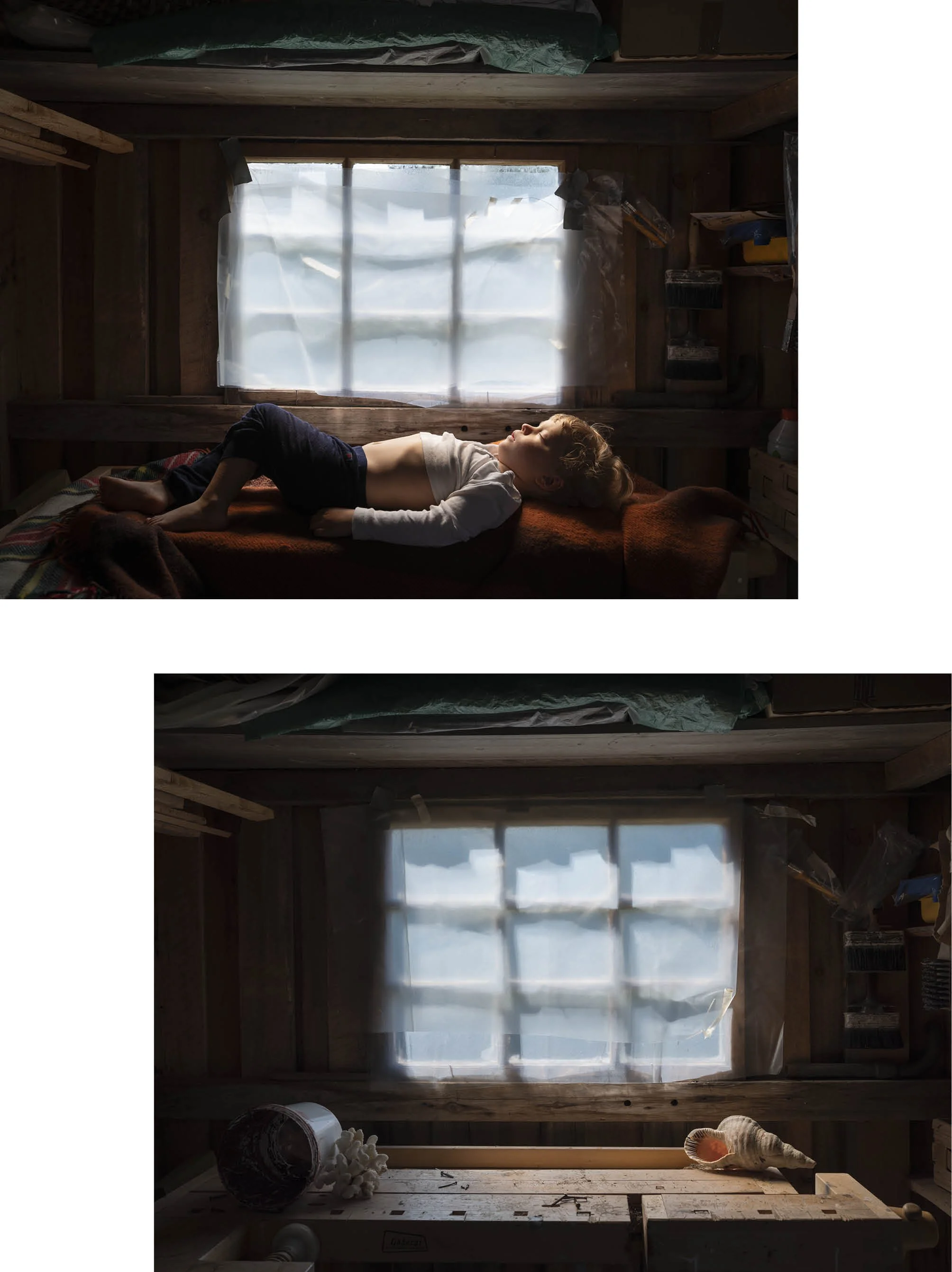 A young boy lying down on a bed in a rustic wooden room with a large window covered by a sheer curtain. Various items, including a shell, a cup, and art supplies, are scattered around.
