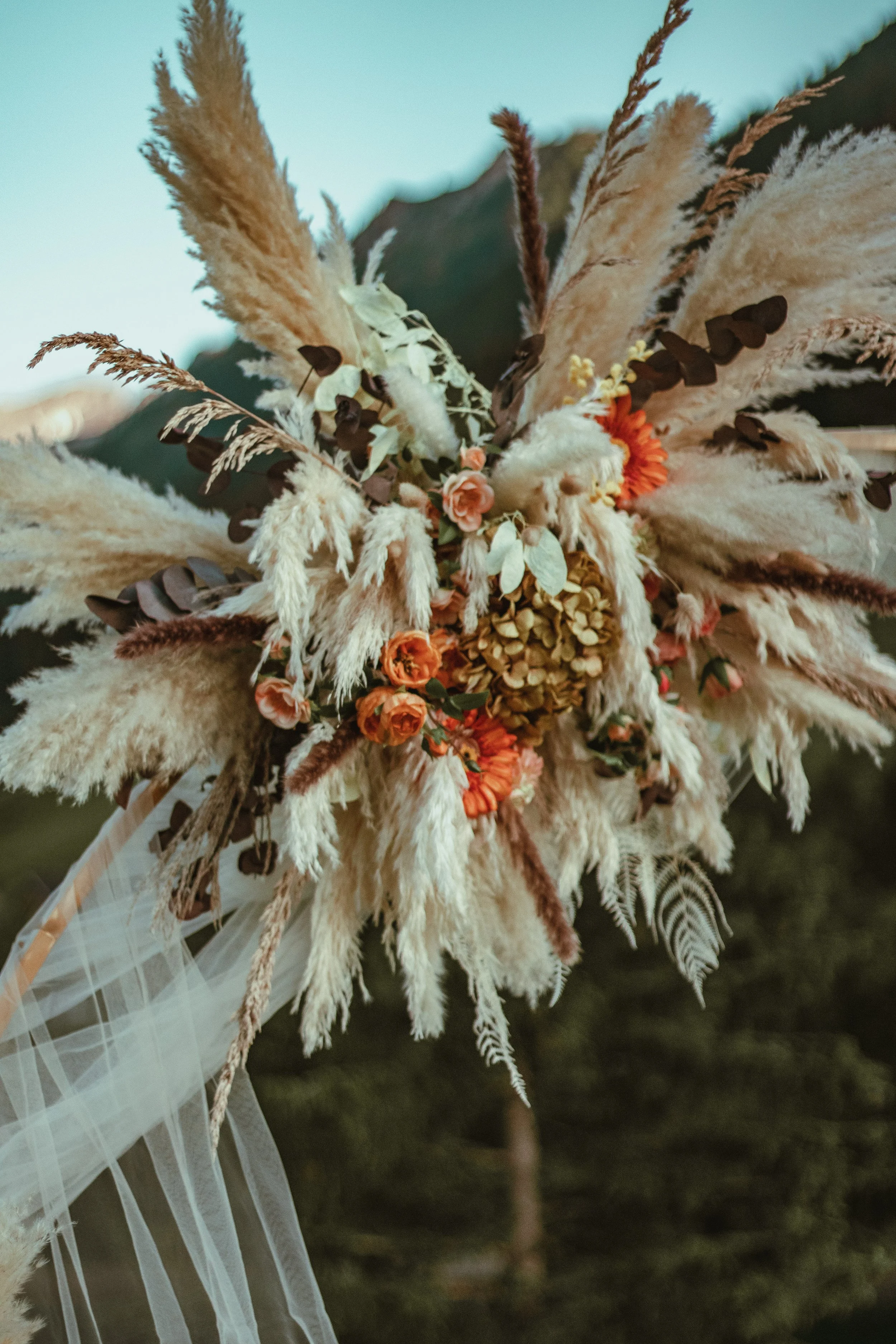 A bouquet of dried flowers and grasses beautifully arranged on a big golden arch for a romantic proposal photoshoot in Switzerland.