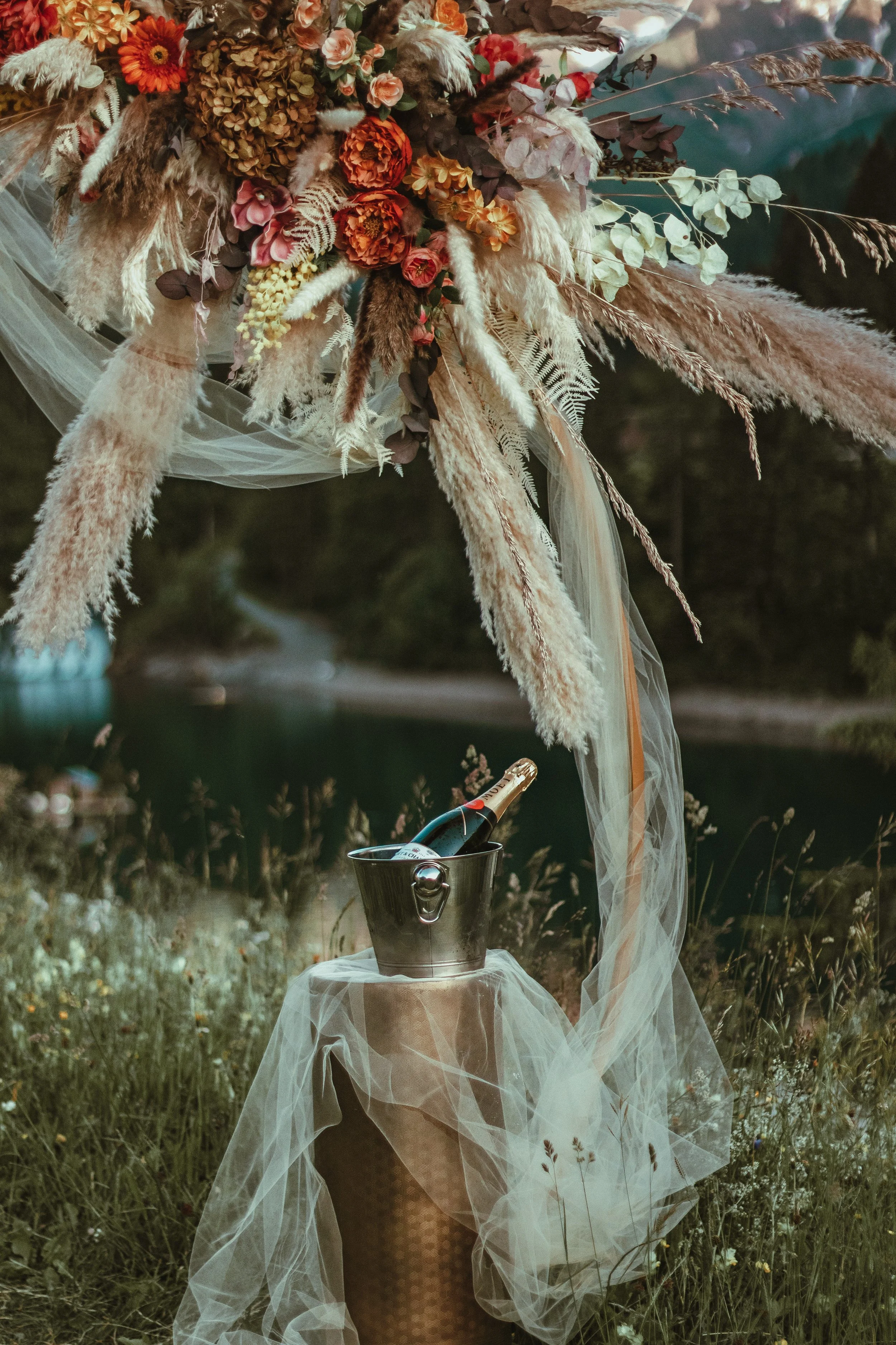A floral arrangement for a romantic proposal with a Moët champagne chilling in an ice bucket at a romantic outdoor proposal setup
