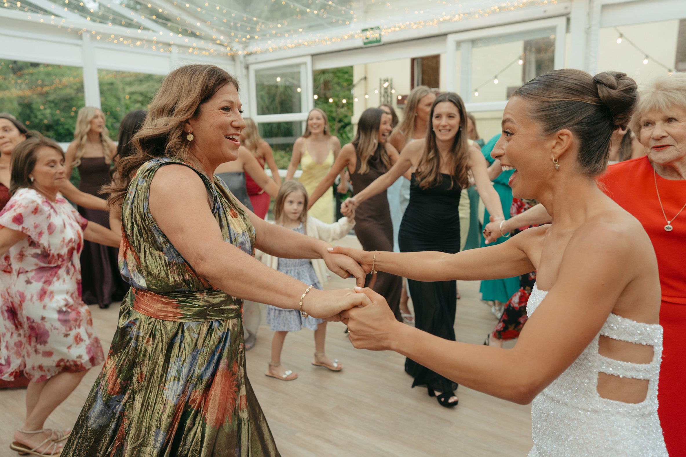 Women dancing and holding hands at a celebration or wedding reception
