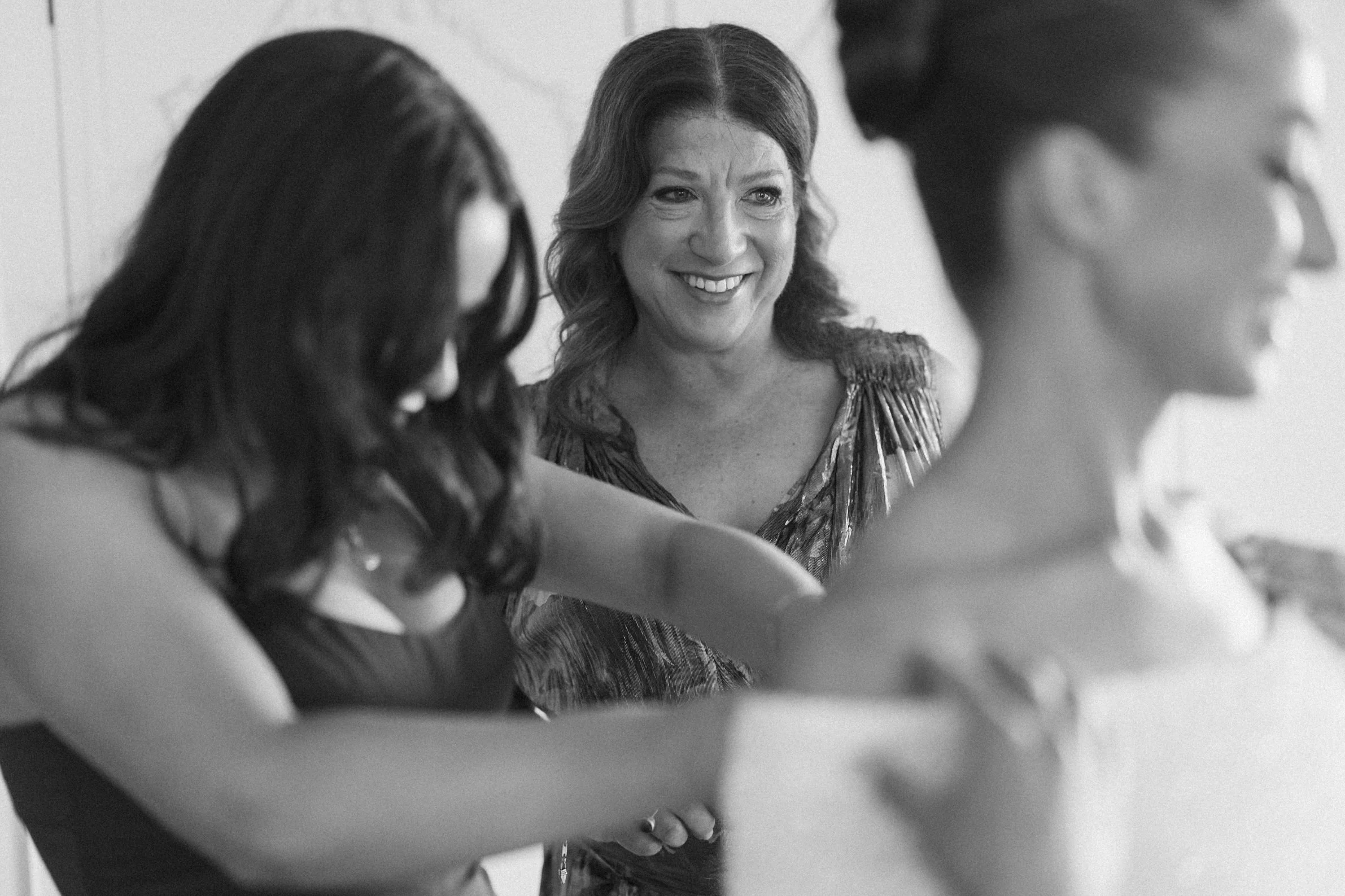 Three women participating in a circle, one woman smiling and looking at the others, in black and white.
