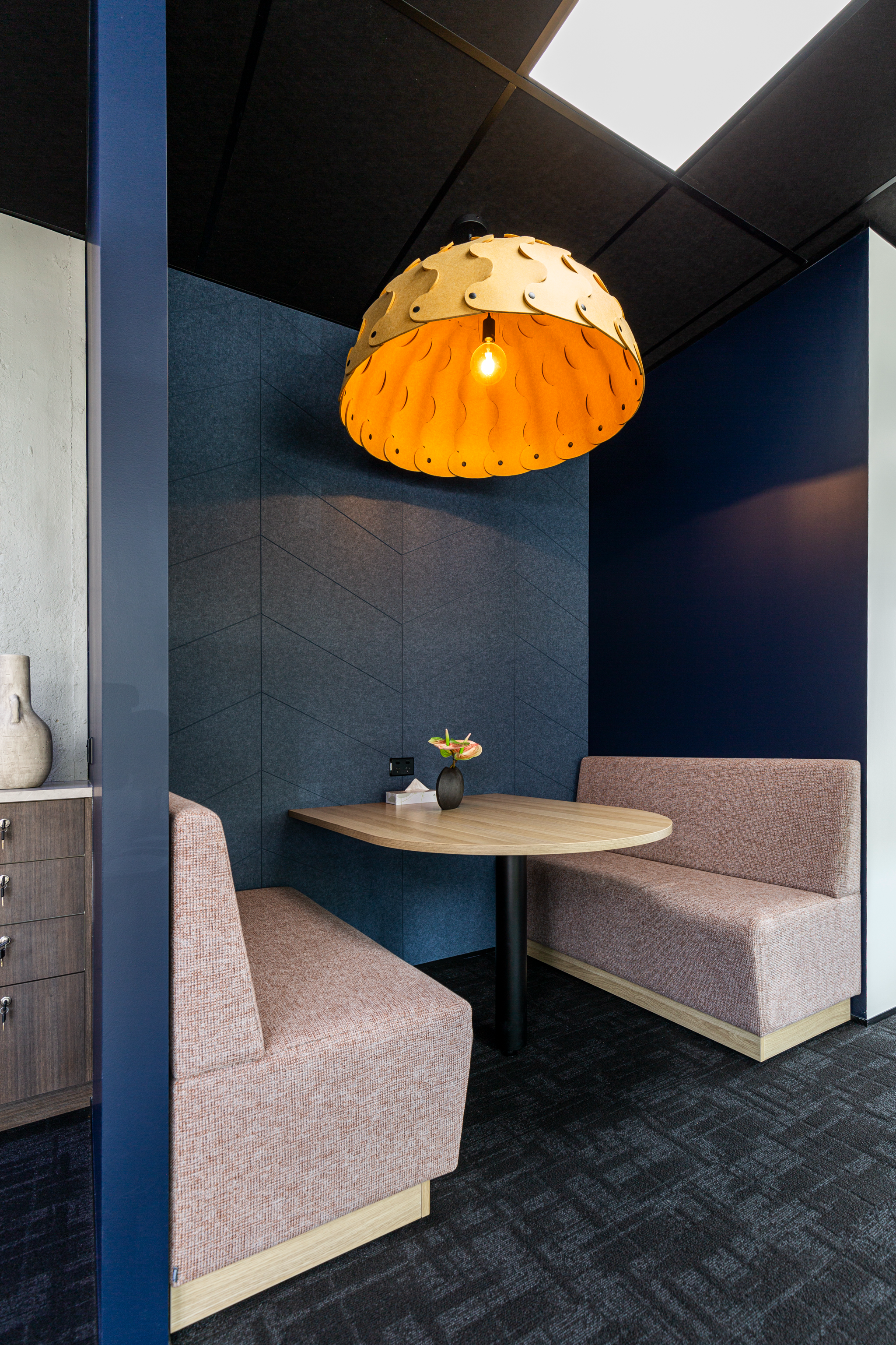 Office meeting booth with pink banquette seating, acoustic panels and statement amber pendant, Barfoot Thompson Otahuhu
