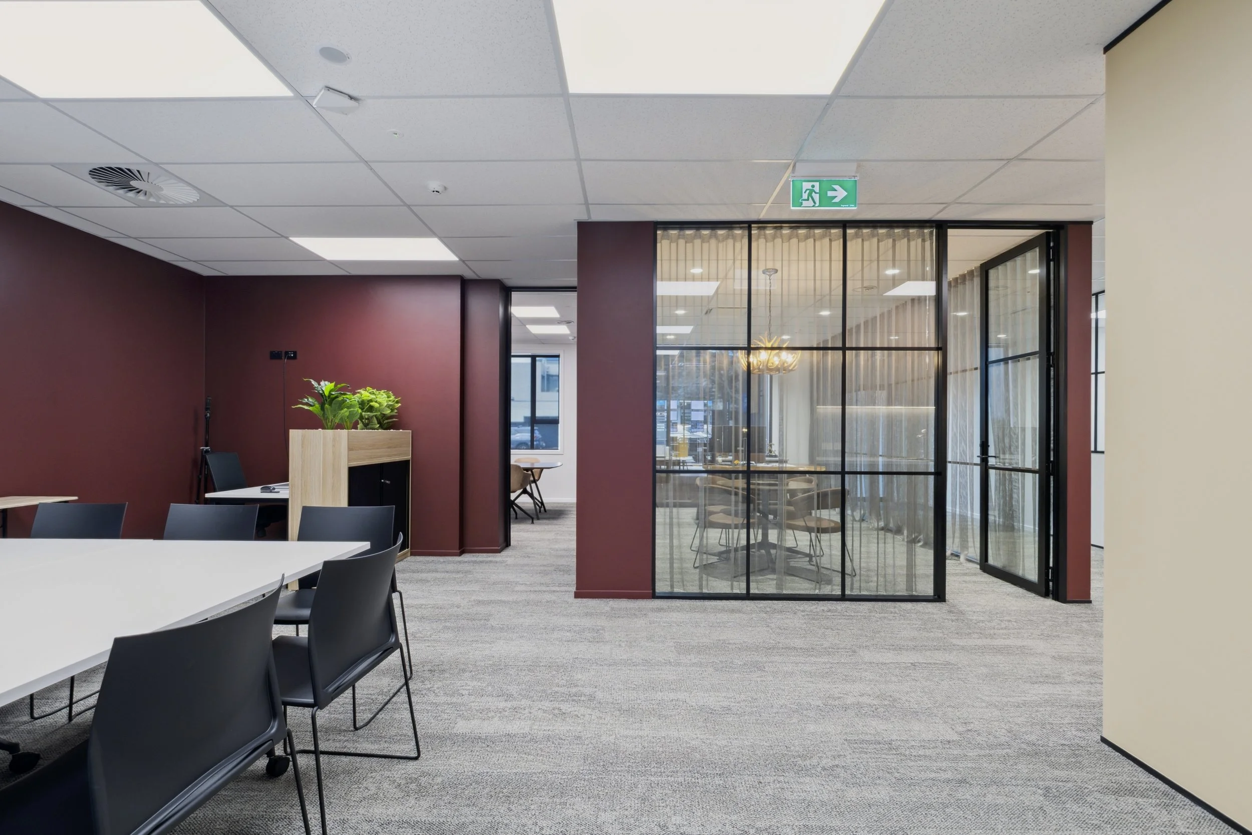 Open plan meeting/auction area with burgundy accent wall and black steel glass partition, Barfoot Thompson Pukekohe
