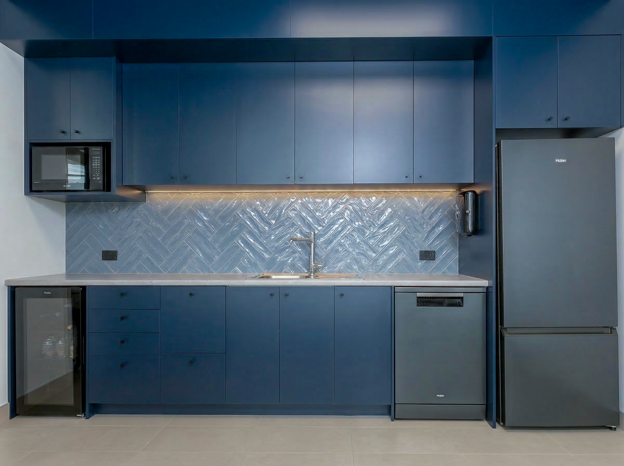 Staff kitchen with navy blue cabinetry and herringbone glazed tile splashback, Barfoot Thompson Otahuhu commercial fitout