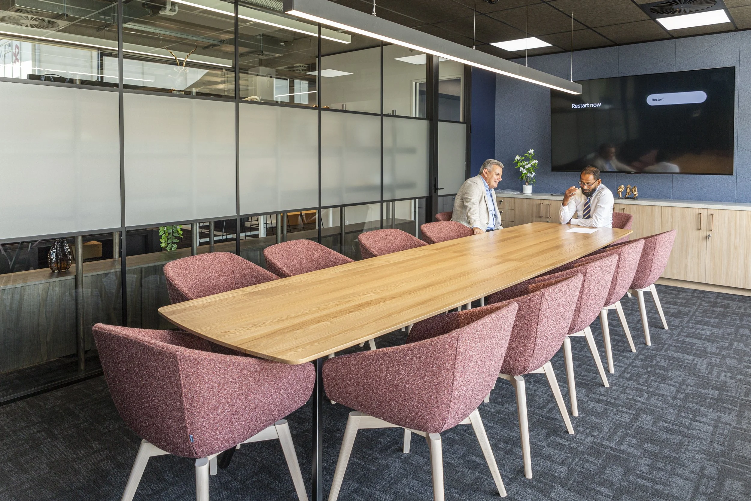 Commercial boardroom with timber table, pink upholstered chairs and black steel glazing, Barfoot Thompson Otahuhu
