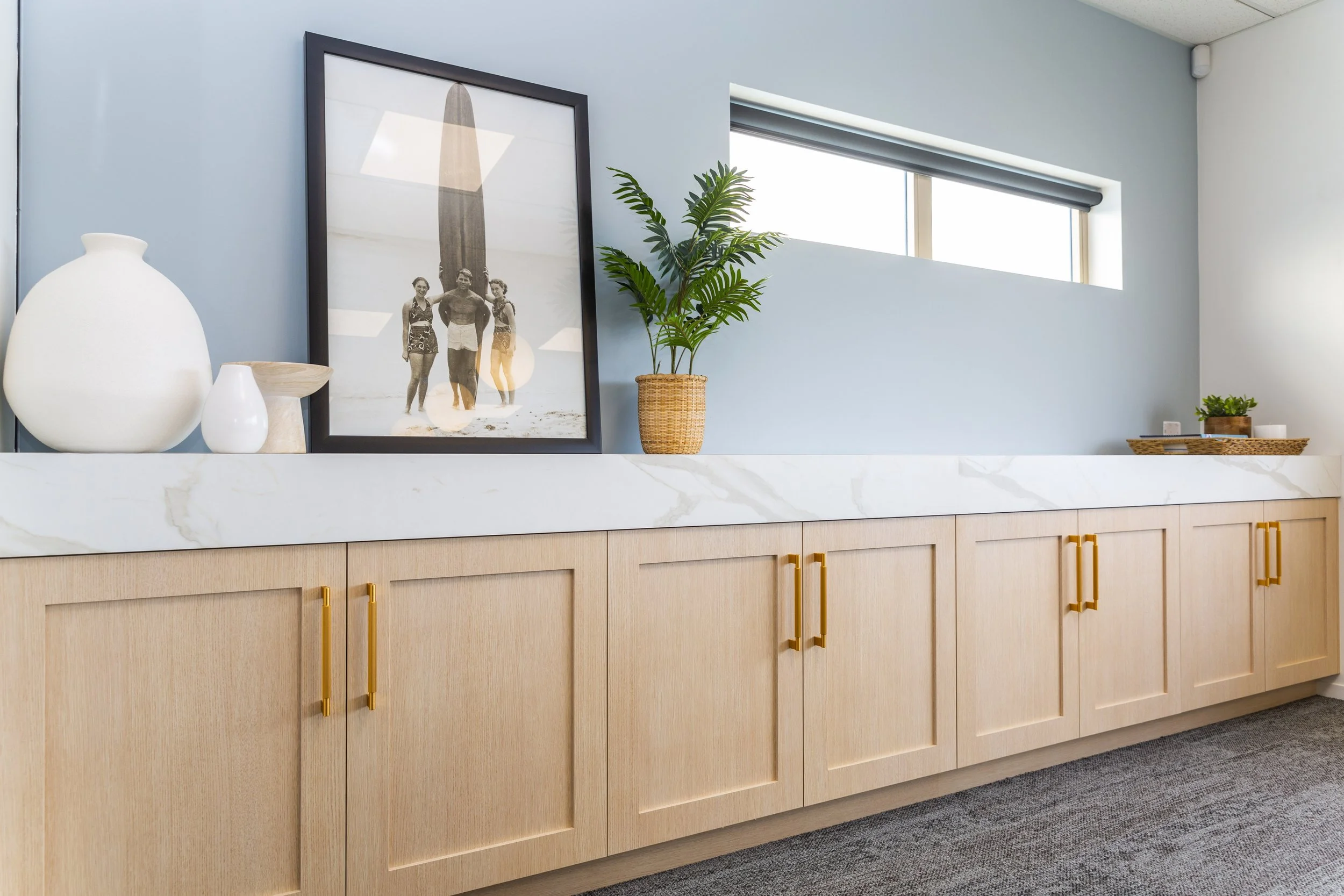 Coastal styled office credenza with pale blue feature wall and marble benchtop, Whangaparaoa commercial interior