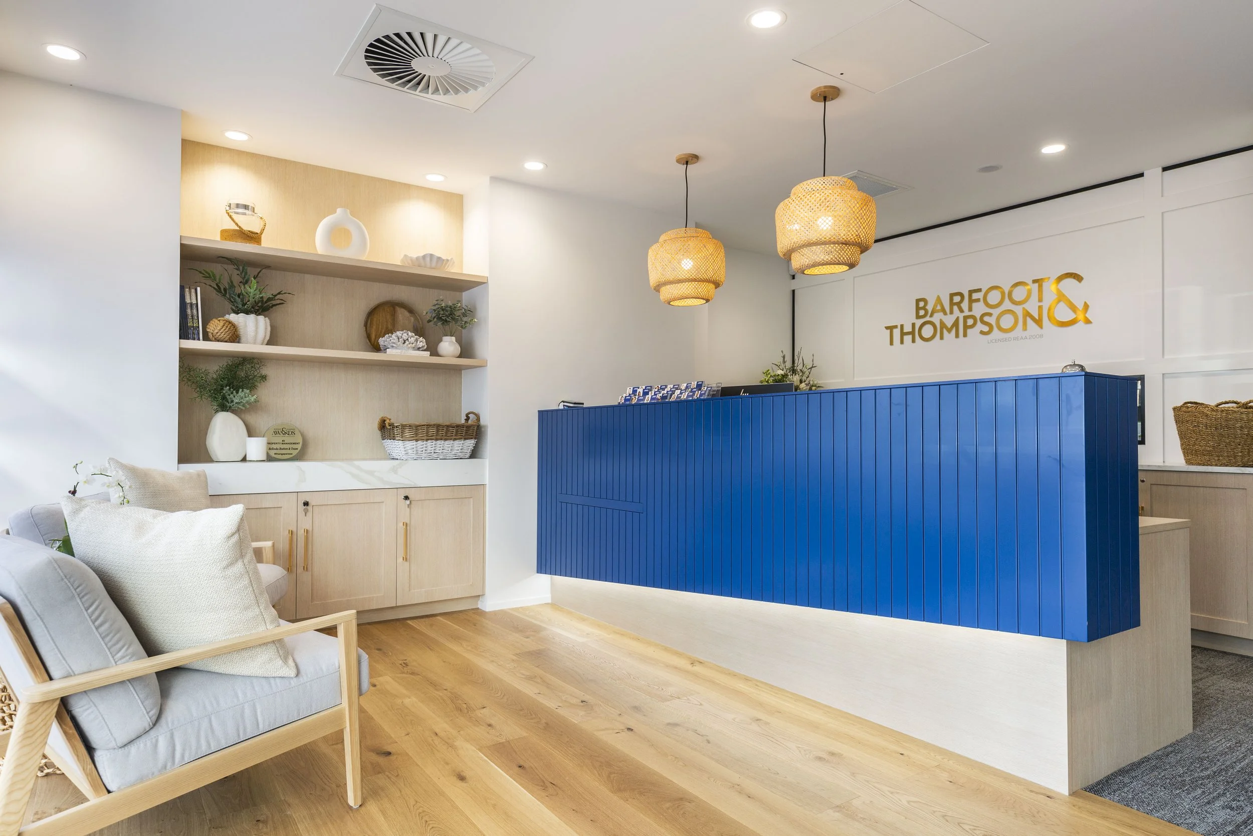 Hamptons-style reception with blue ribbed desk and timber joinery, Barfoot Thompson Whangaparaoa, commercial interior design